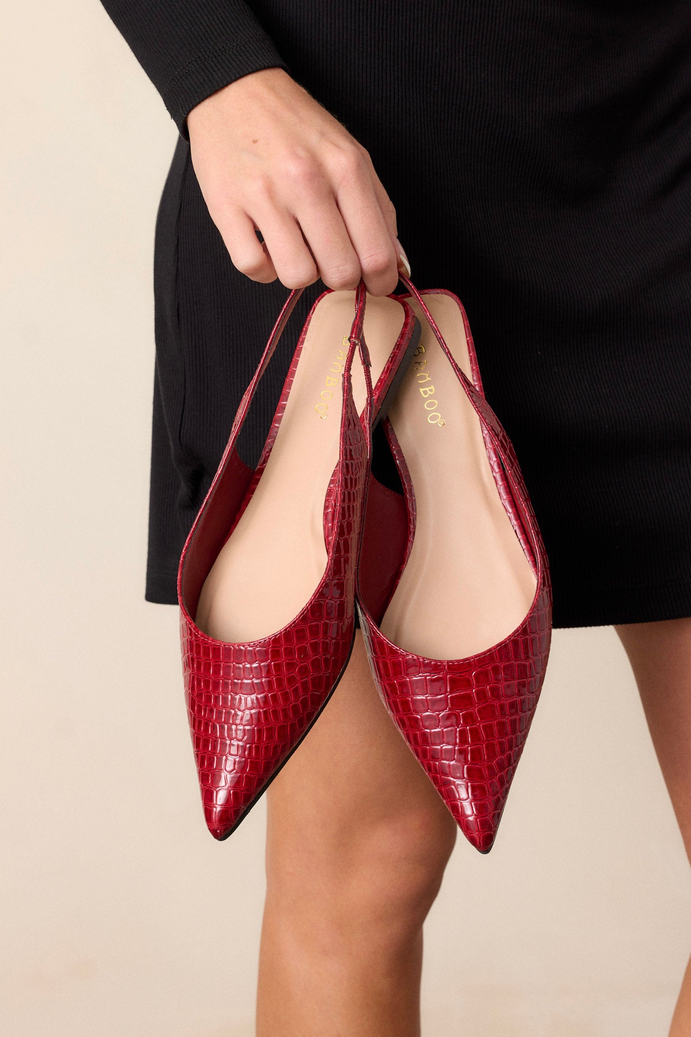 Front view of these red flats featuring a pointed toe, a faux crocodile leather, a slingback-style strap, and a sleek red color.