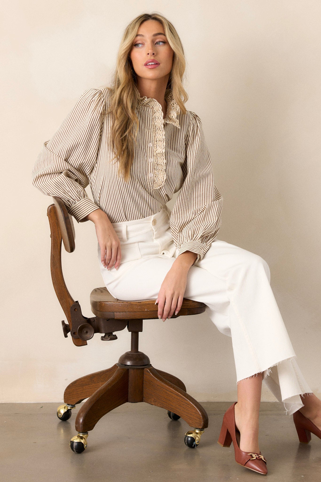 Seated view of these ivory jeans that feature a high waisted design, a button & zipper closure, belt loops, functional front & back pockets, a wide leg design, and a raw hemline