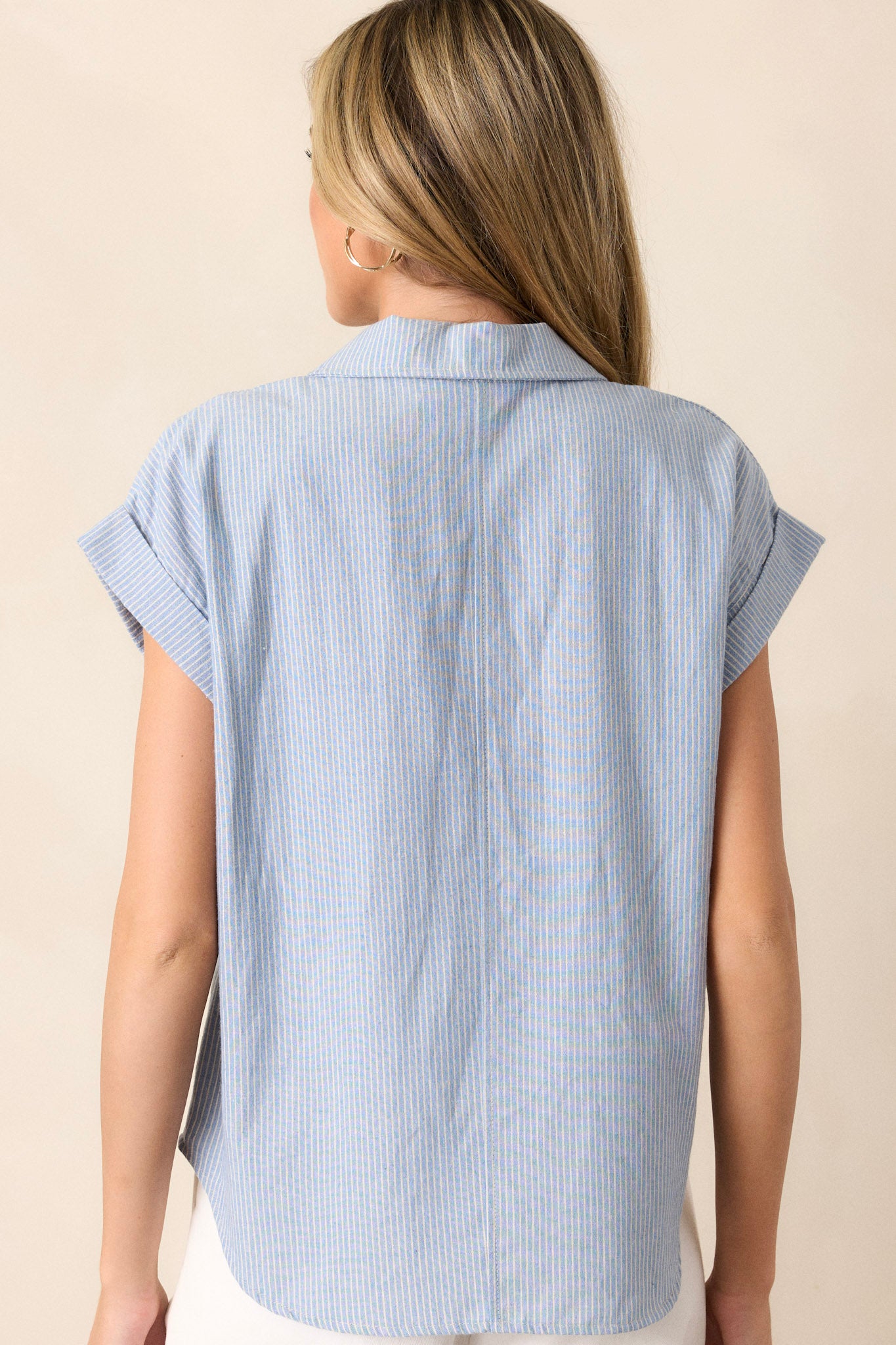 Back view of this light blue stripe top that features a collared v-neckline, a functional button front, a vertical stripe pattern, functional bust pockets, and cuffed short sleeves.