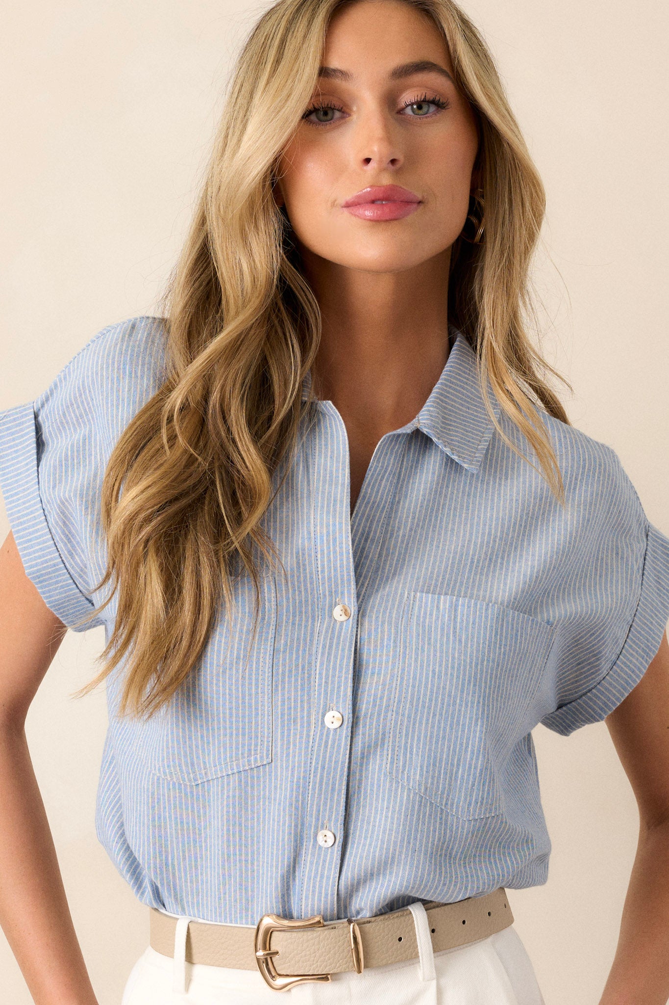 This light blue stripe top features a collared v-neckline, a functional button front, a vertical stripe pattern, functional bust pockets, and cuffed short sleeves.