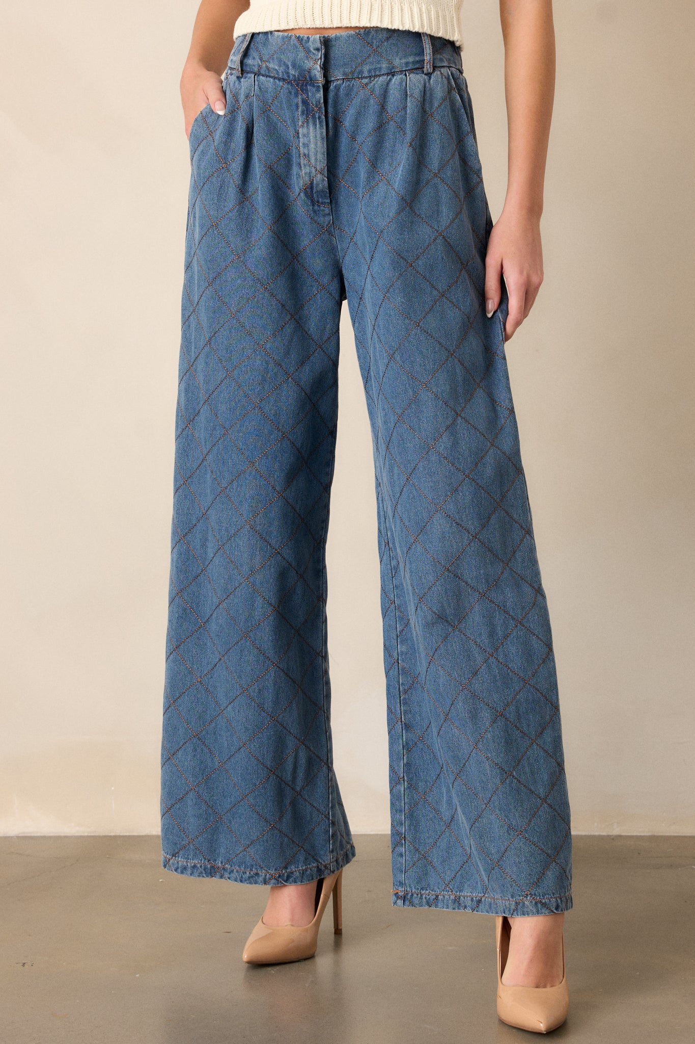 Front view of quilted jeans featuring a high waisted design, a hook and bar closure, functional belt loops, hip pockets, a quilted design and a wide leg.