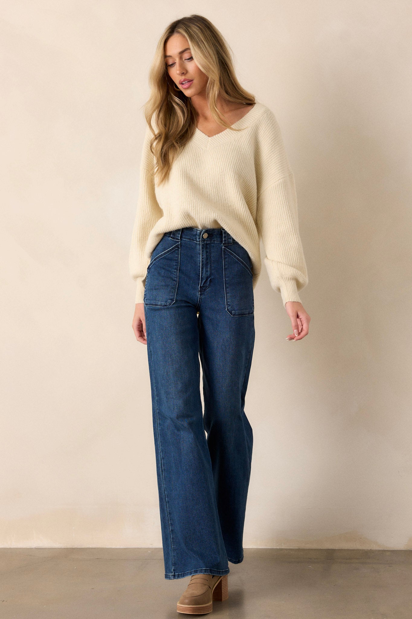 These dark wash jeans feature a high waisted design, classic button zipper closure, belt loops, functional front patch pockets, and a flare leg.