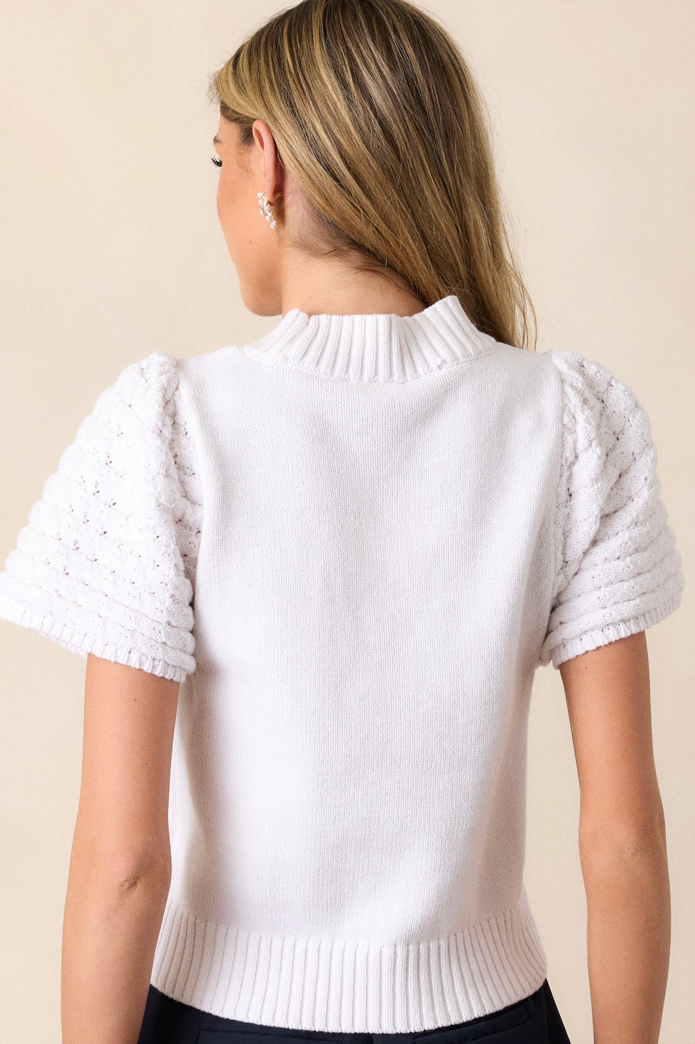 Back view of a white short sleeve sweater highlighting the ribbed collar and cap sleeves.