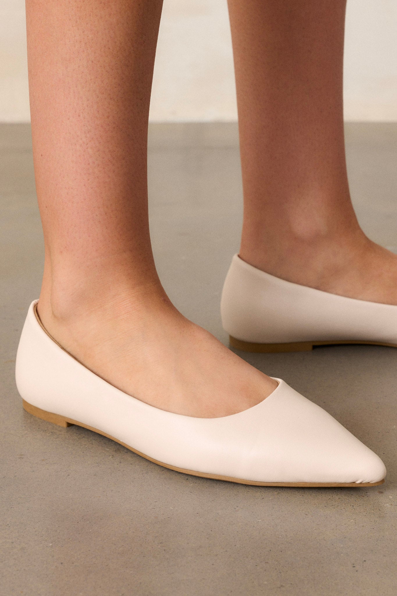 These flats feature a pointed toe, a faux leather material, and a sleek ivory color.