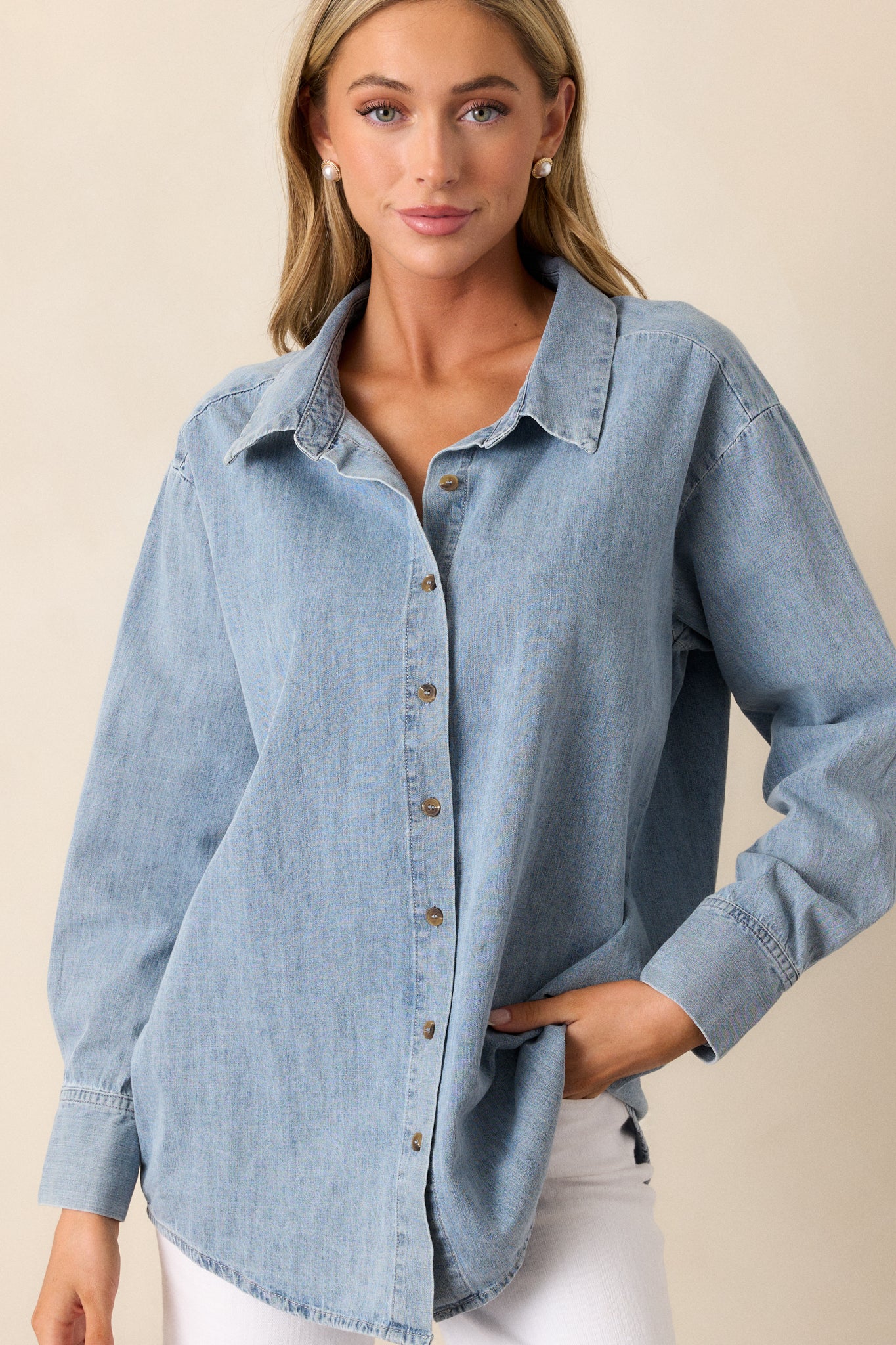 Front view of a chambray top featuring a collared neckline, functional buttons down the front, long sleeves with buttoned cuffs, and a scoop bottom hemline