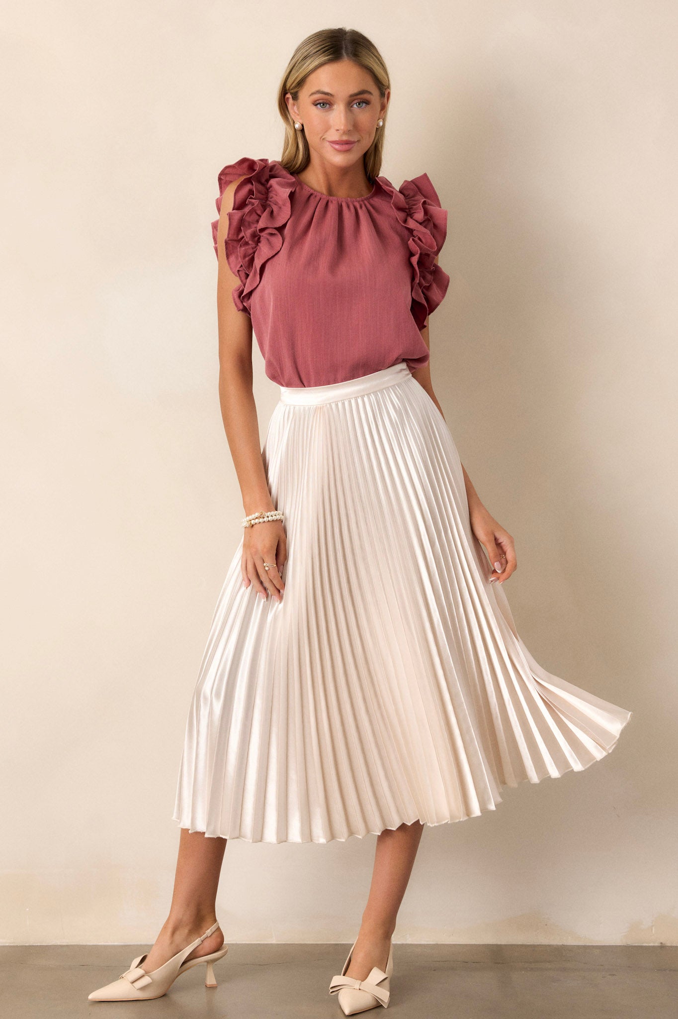 This ivory midi skirt features a high waisted design, an elastic insert at the back of the waist, a discrete side zipper, and is heavily pleated throughout.