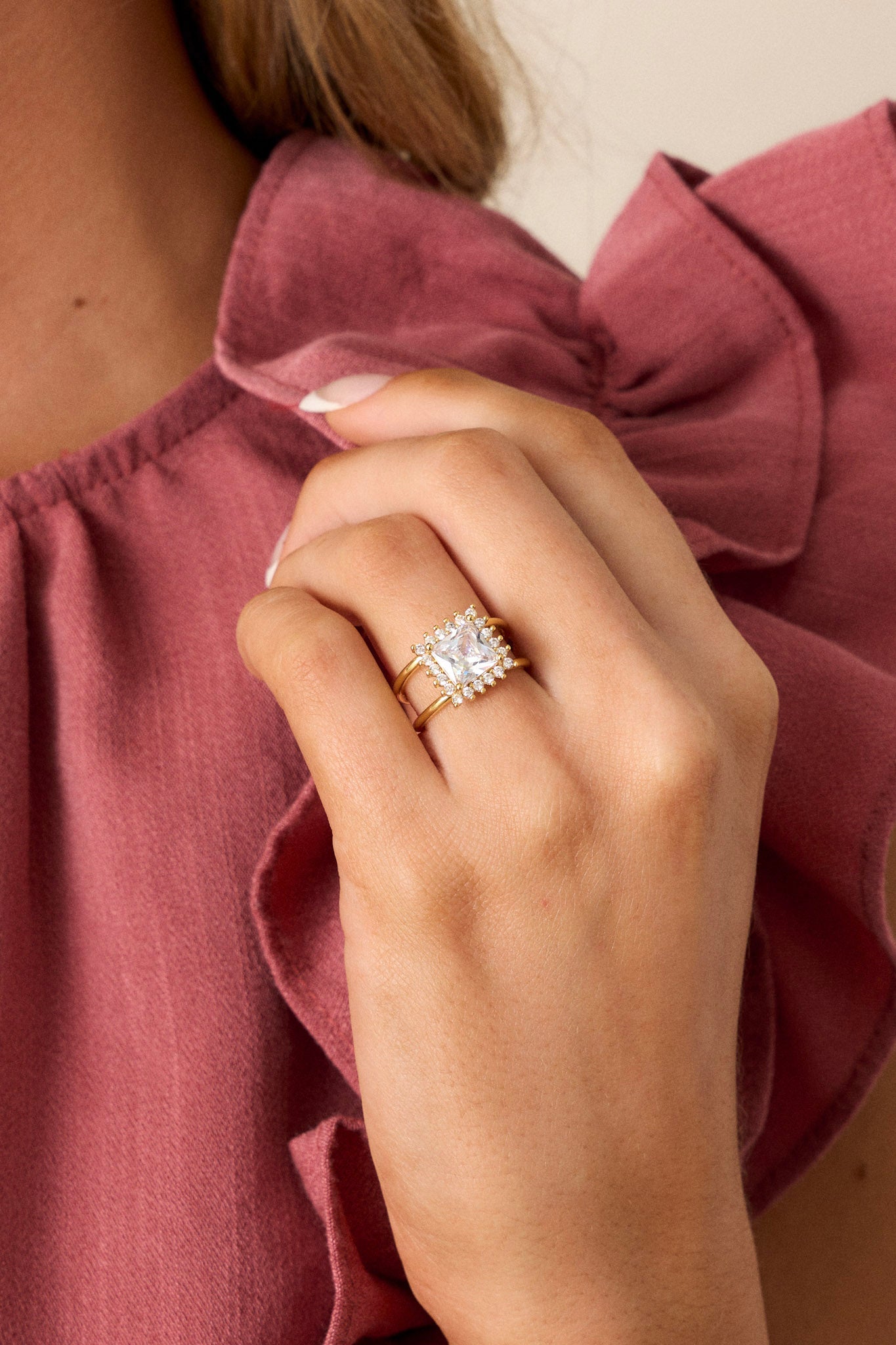 Close-up of this ring that features gold hardware, a square rhinestones with smaller rhinestones around it, and an adjustable band.