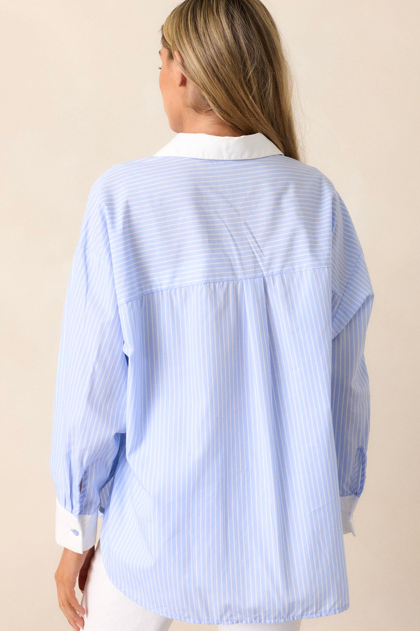 Back view of the stripe button-front shirt highlighting the oversized fit, vertical stripe design, and the side slits in the hem.