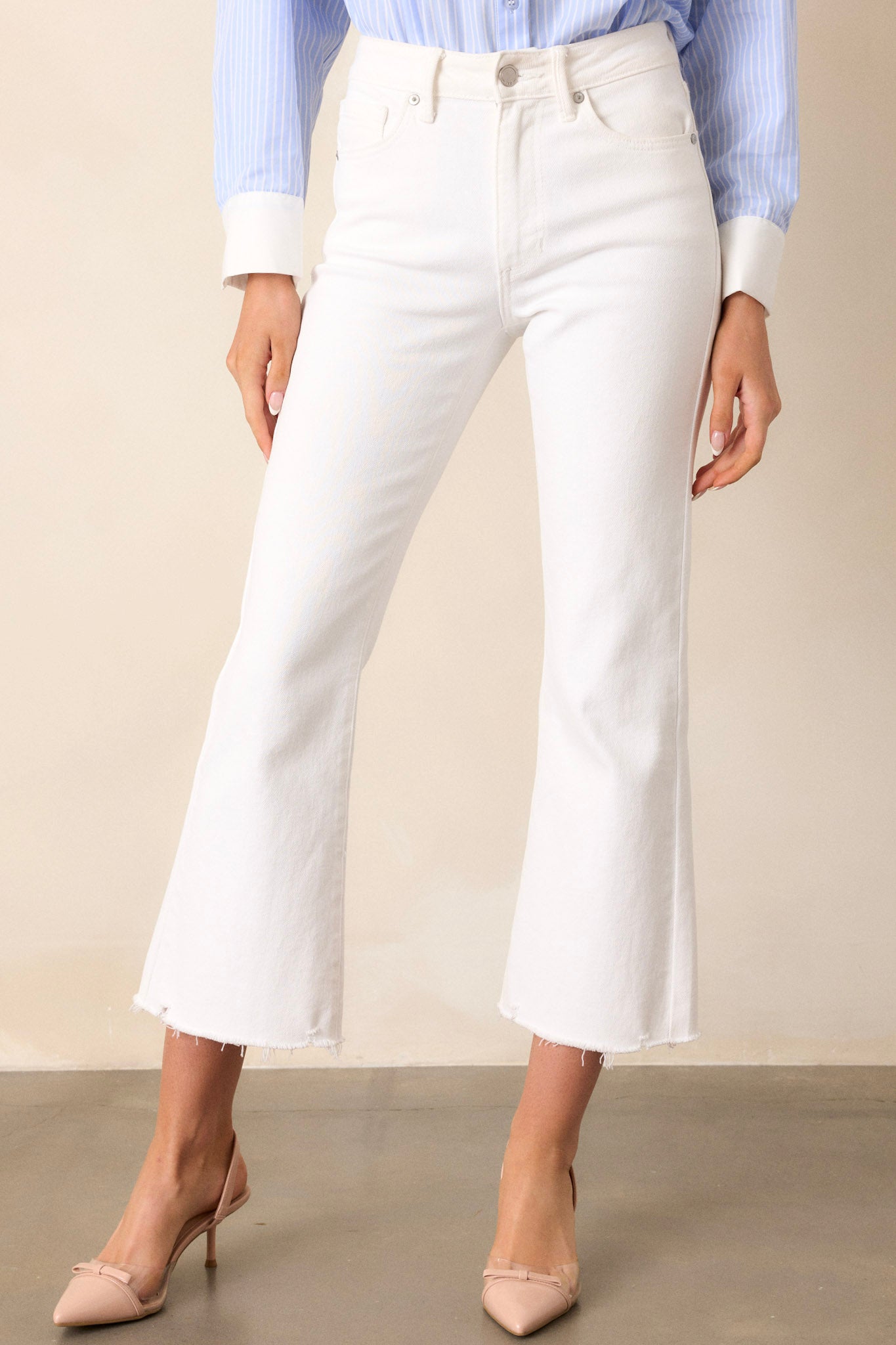 Close up view of these jeans that feature a high waisted design, classic button & zipper closure, belt loops, functional front & back pockets, a cropped length, and a raw hemline.