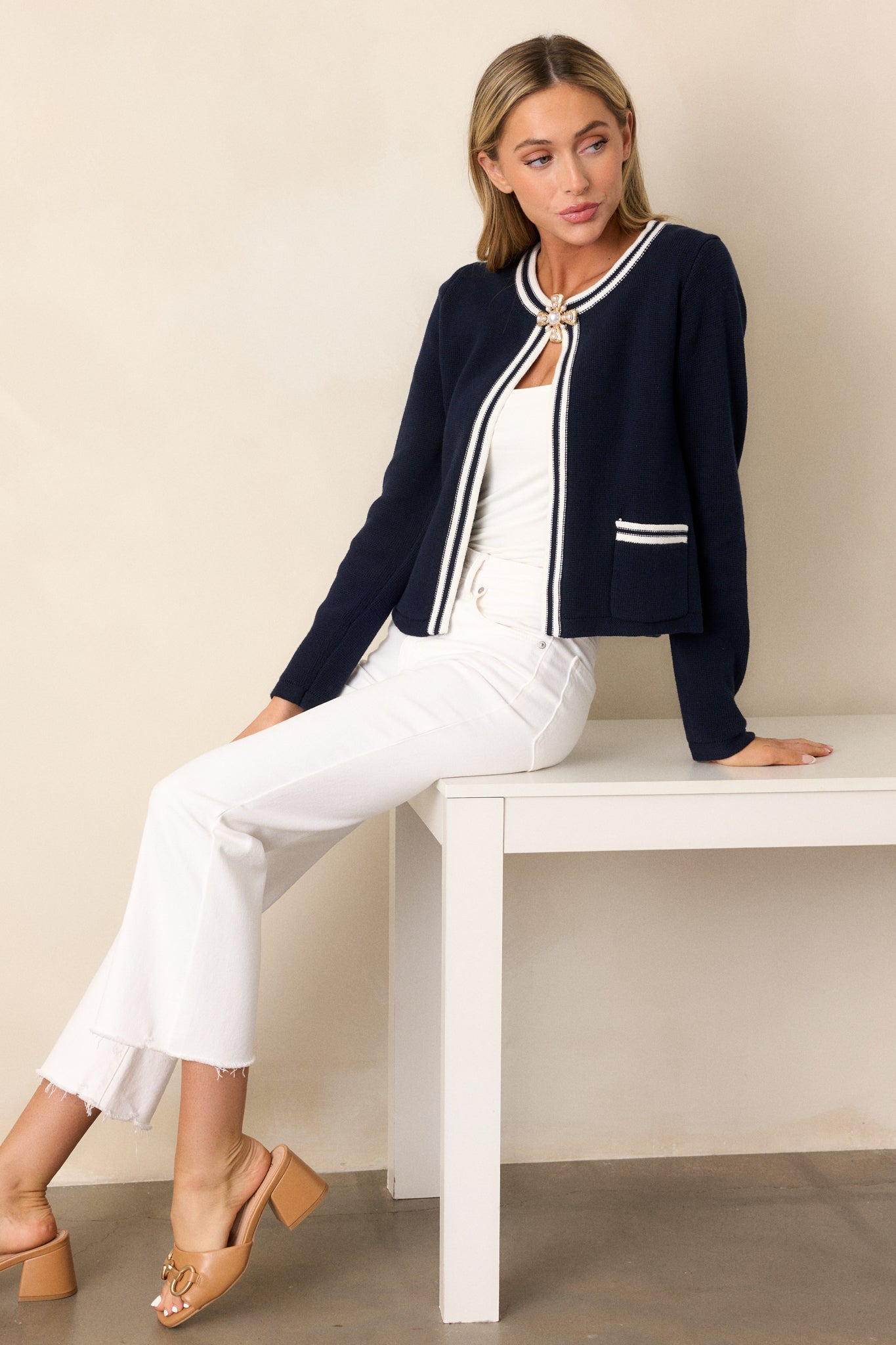 Full body view of a navy knit cardigan with an open knit design, striped detailing, two functional front pockets, and long cuffed sleeves