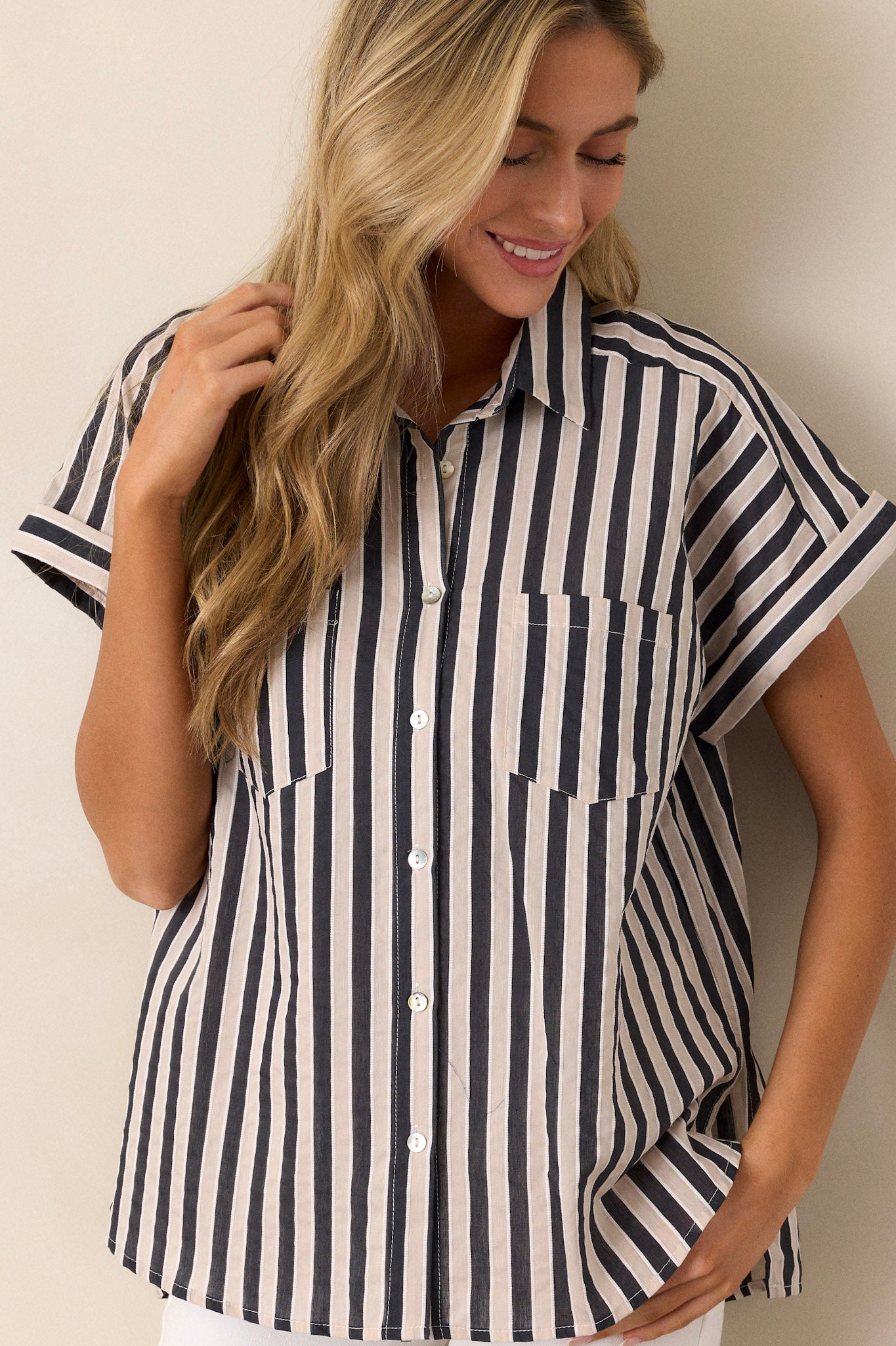 Front view of a black stripe top featuring a collared neckline, a full button front, functional breast pockets, a vertical stripe design, cuffed short sleeves, and a split scooped hemline.