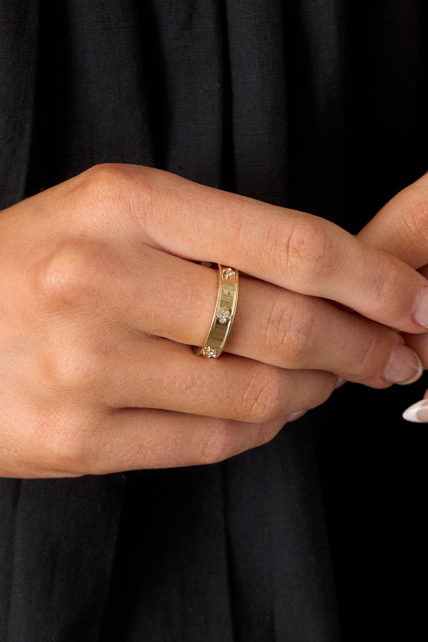 Close-up view of this gold ring, highlighting the sunken center and sparkling floral rhinestone accents against the shiny gold surface.