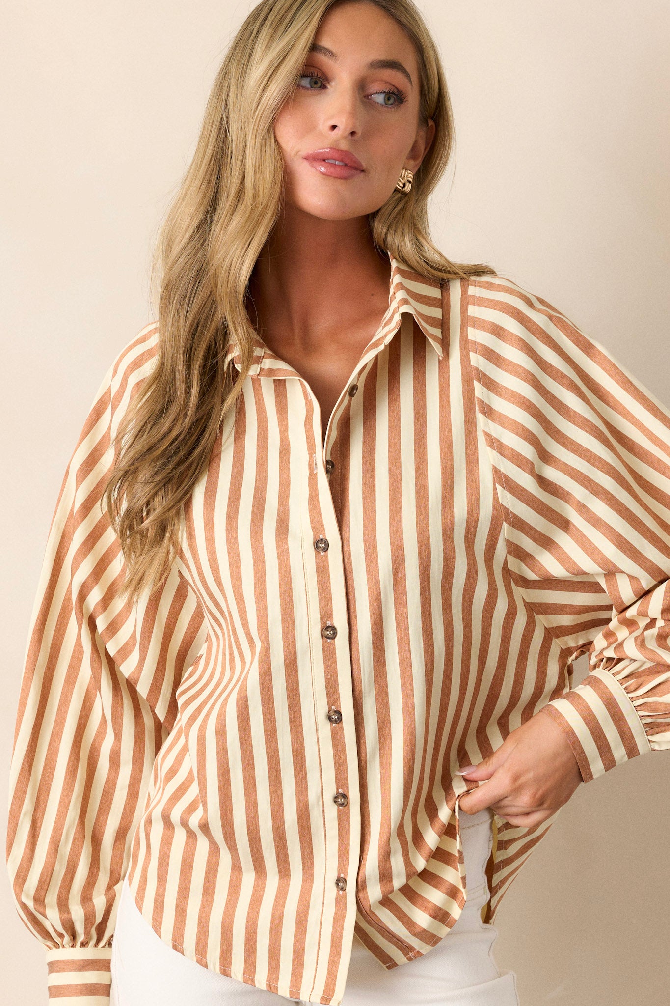 Full front view of a tan stripe top featuring a collared neckline, functional button front, vertical tan and white stripe design, and cuffed dolman long sleeves