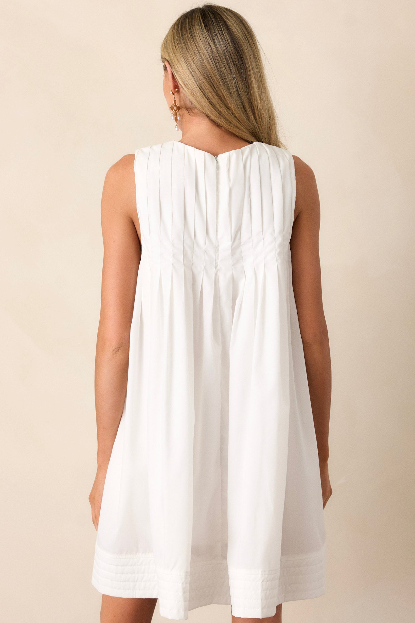 A view of the back of the white mini dress, highlighting the clean lines and the zipper closure that continues from the front design.