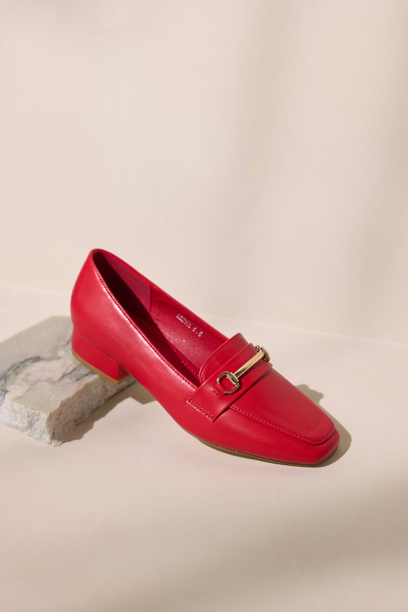 Overhead view of these red loafers that feature a slip on design, a small heel, a square toe, and gold hardware.