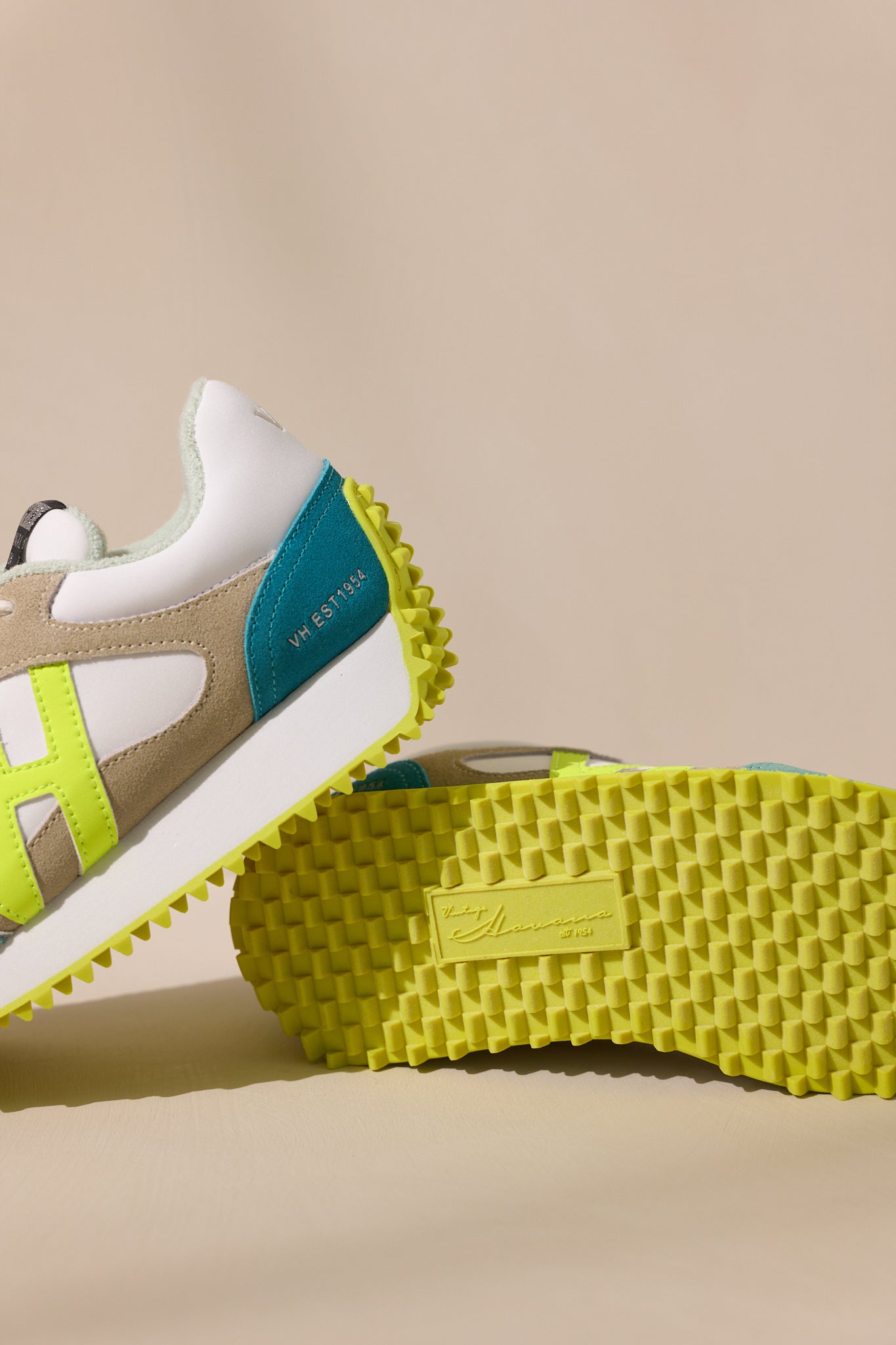 Below view of these neon yellow sneakers feature a rounded toe, functional laces, subtle pops of color, a slight platform, and a heavily textured sole.