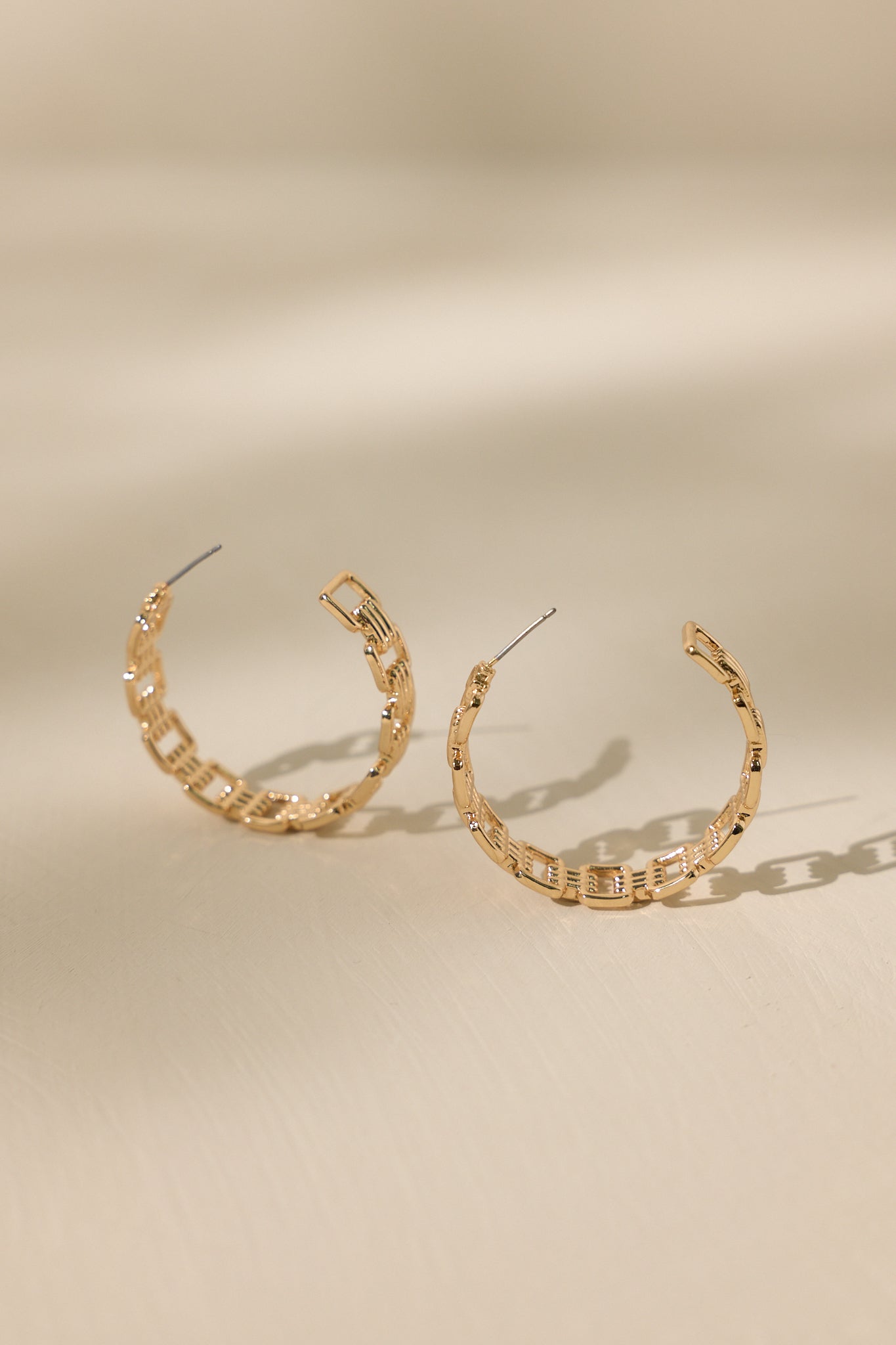 Stand alone of these hoop earrings featuring an incomplete hoop design, square shaped links, and secure post backings.