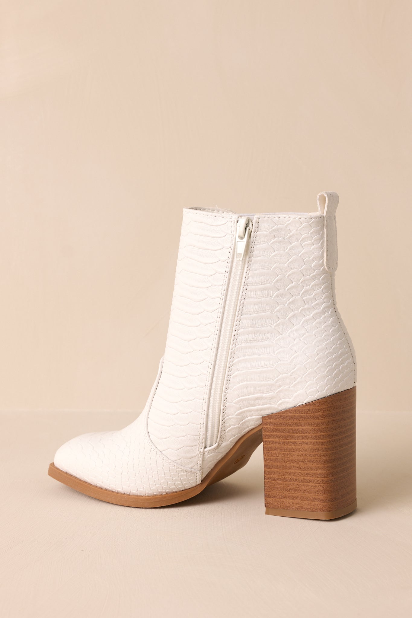 Close-up of  these white ankle boots that feature a side zipper and an elastic side insert.