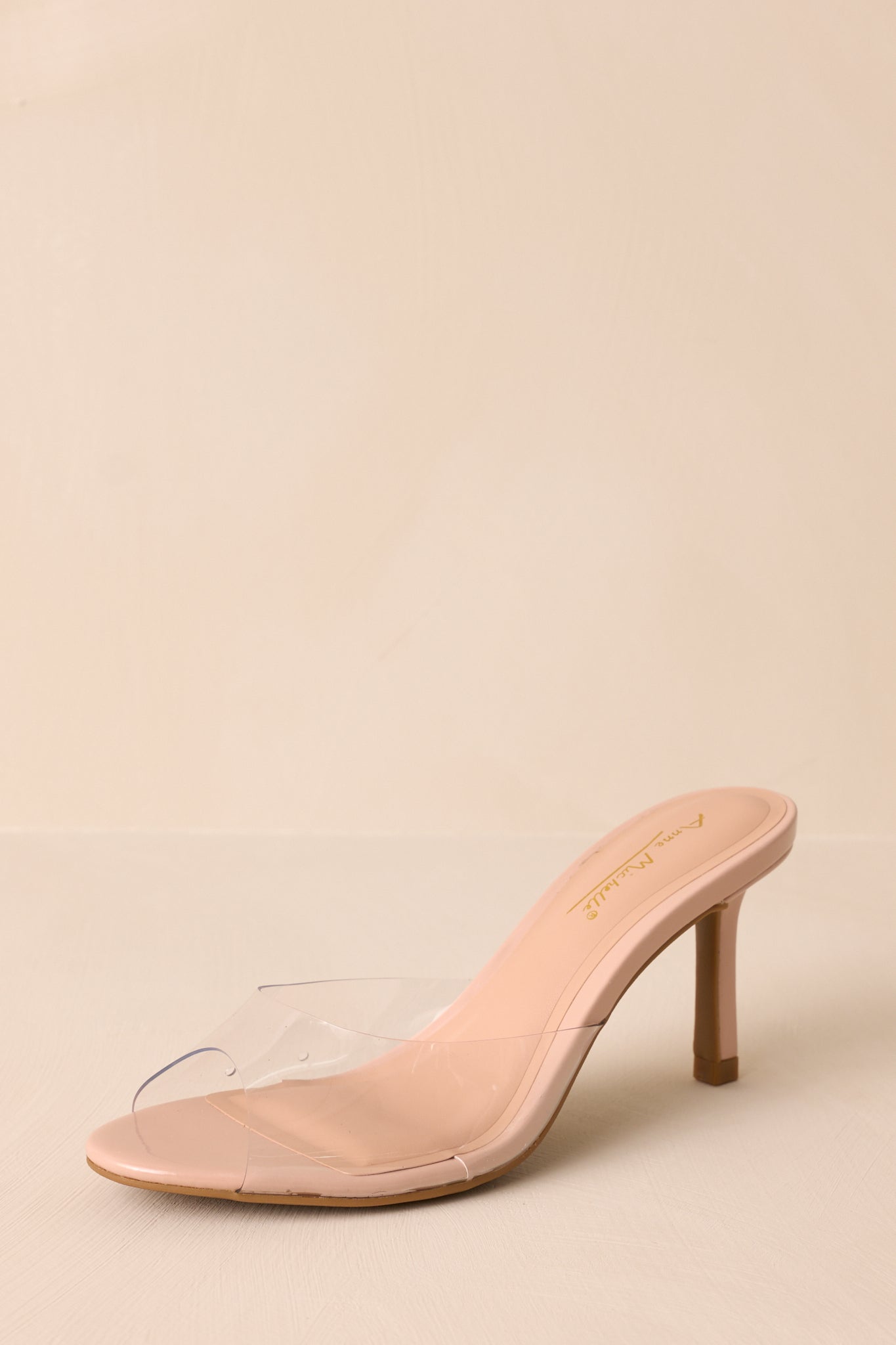 Front angled view of these nude heels that feature a rounded toe, a clear thick toe strap and extra heel cushioning.