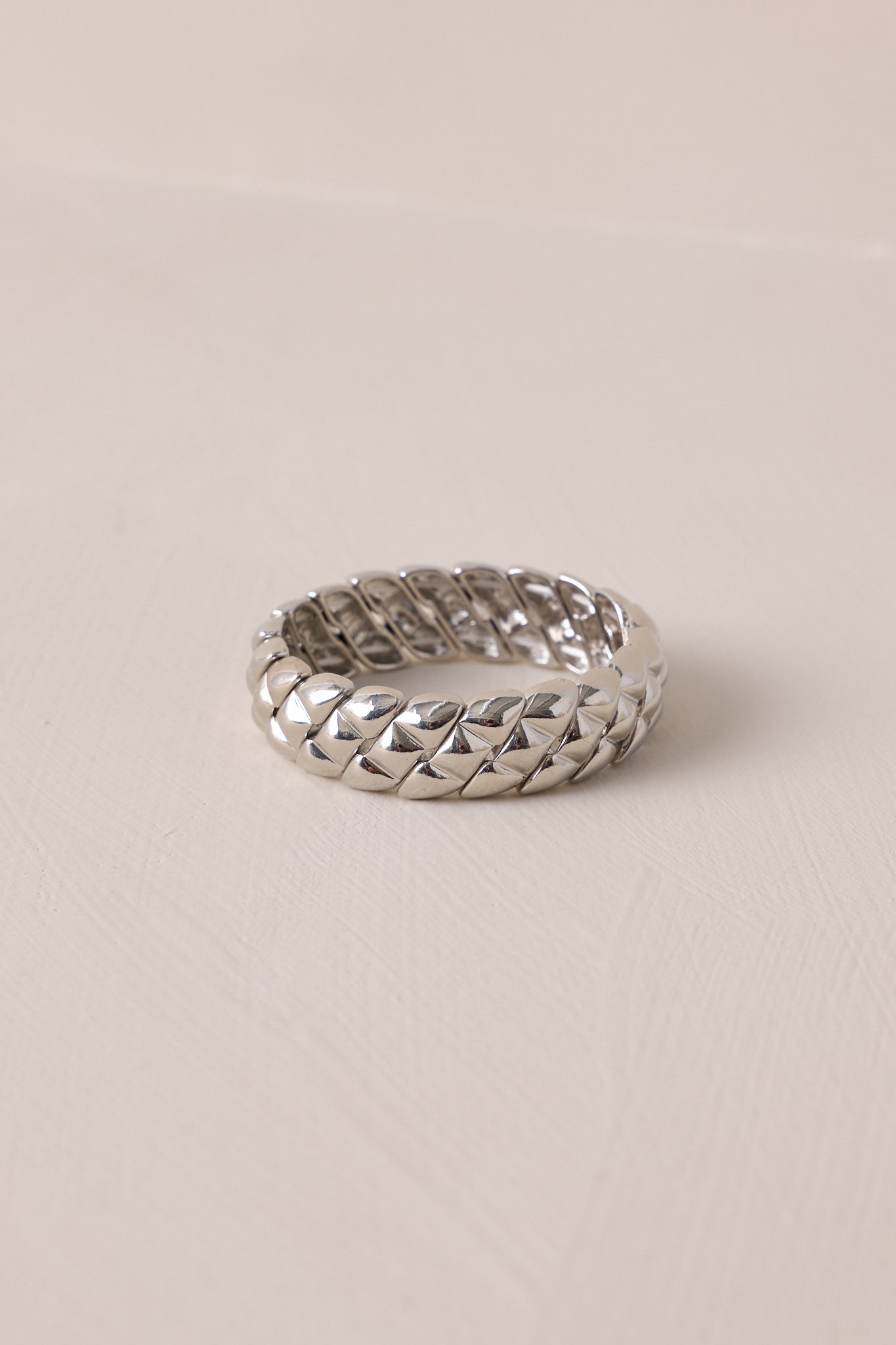 A detailed shot of the silver bracelet, featuring elastic bands for a customizable fit and a stylish braided design that wraps around for a chic, contemporary look.