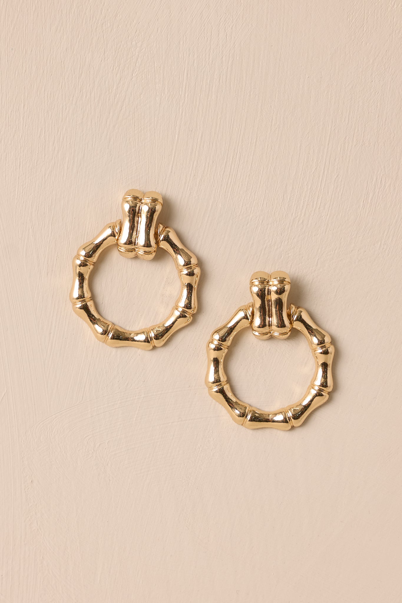 Overhead of these gold earrings that feature textured gold hardware, a textured stud with a connected textured hoop, and secure post backings.