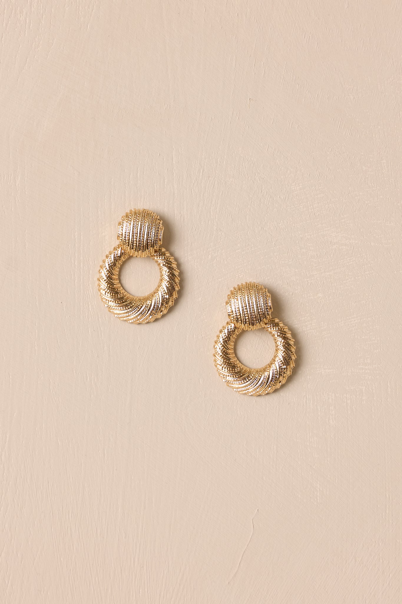 These earrings feature textured gold hardware, a textured stud with attached hoop, and secure post backings.