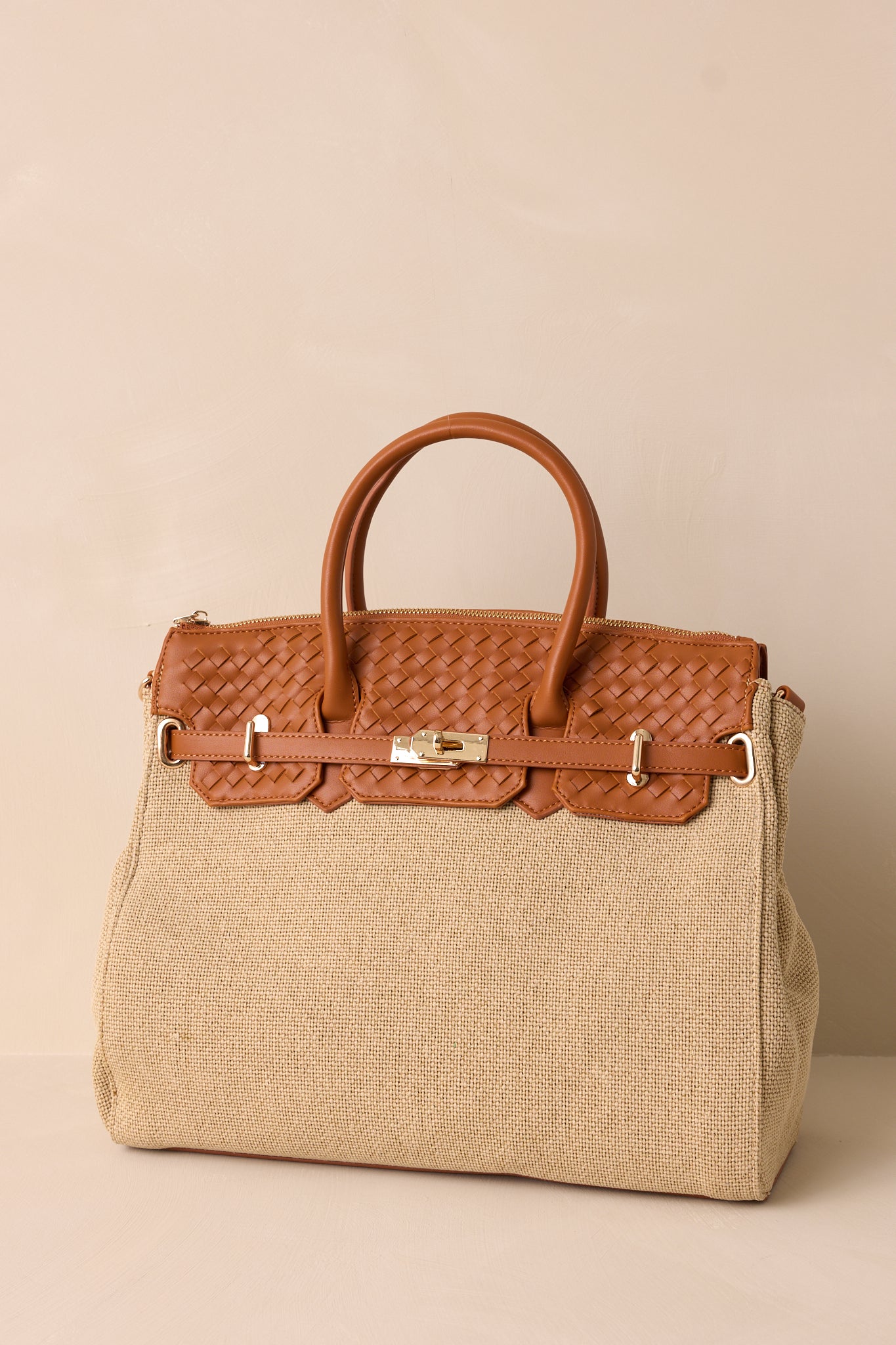 Full length view of the tan structured tote bag featuring a beige woven body, a tan woven faux leather top, gold hardware, and tan handles