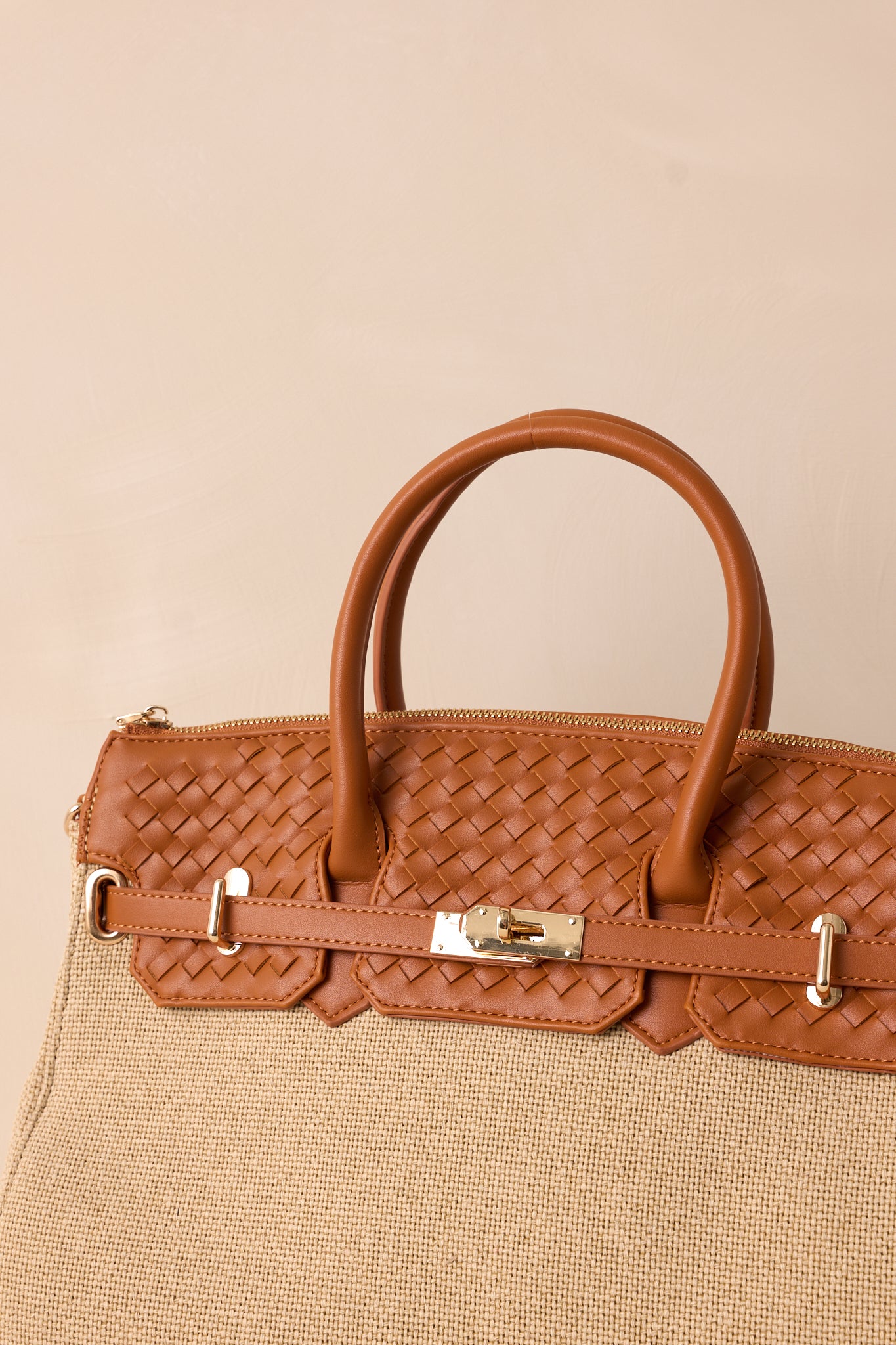 Close-up of the tan structured tote bag focusing on the gold hardware, the beige woven texture, and the tan woven faux leather top