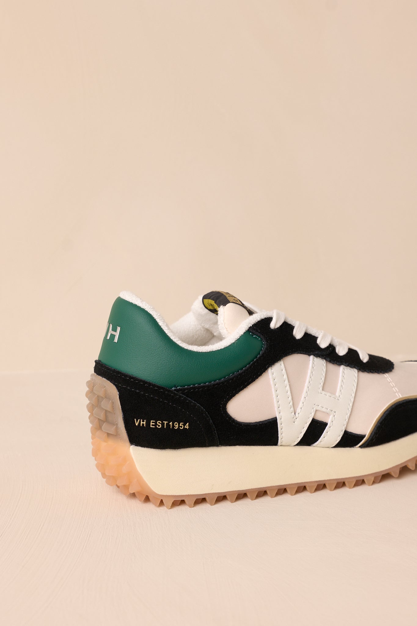 Back view of these green sneakers that feature a rounded toe, functional laces, subtle pops of color, a slight platform, and a heavily textured sole.