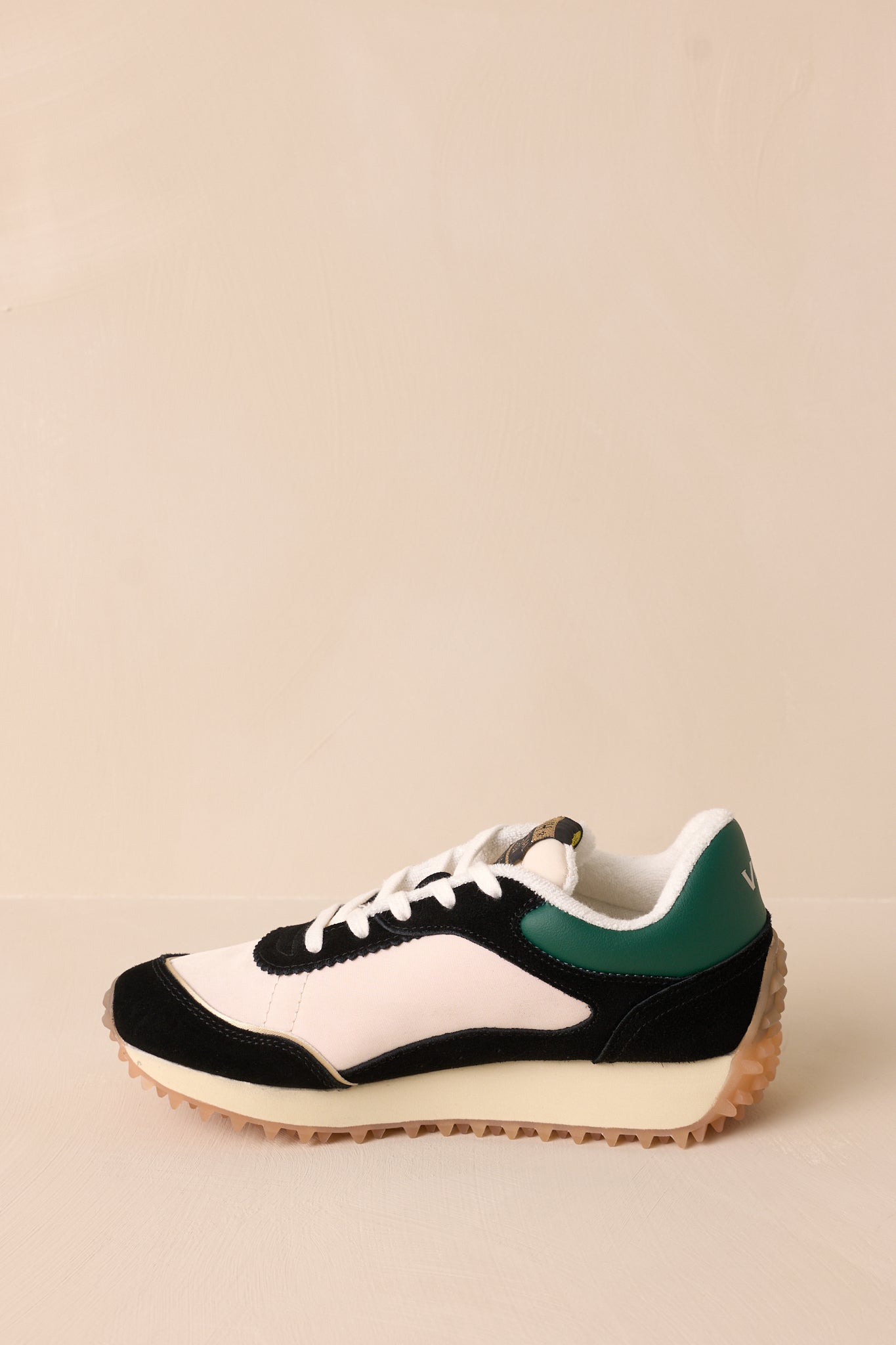 Inside side view of these green sneakers that feature a rounded toe, functional laces, subtle pops of color, a slight platform, and a heavily textured sole.