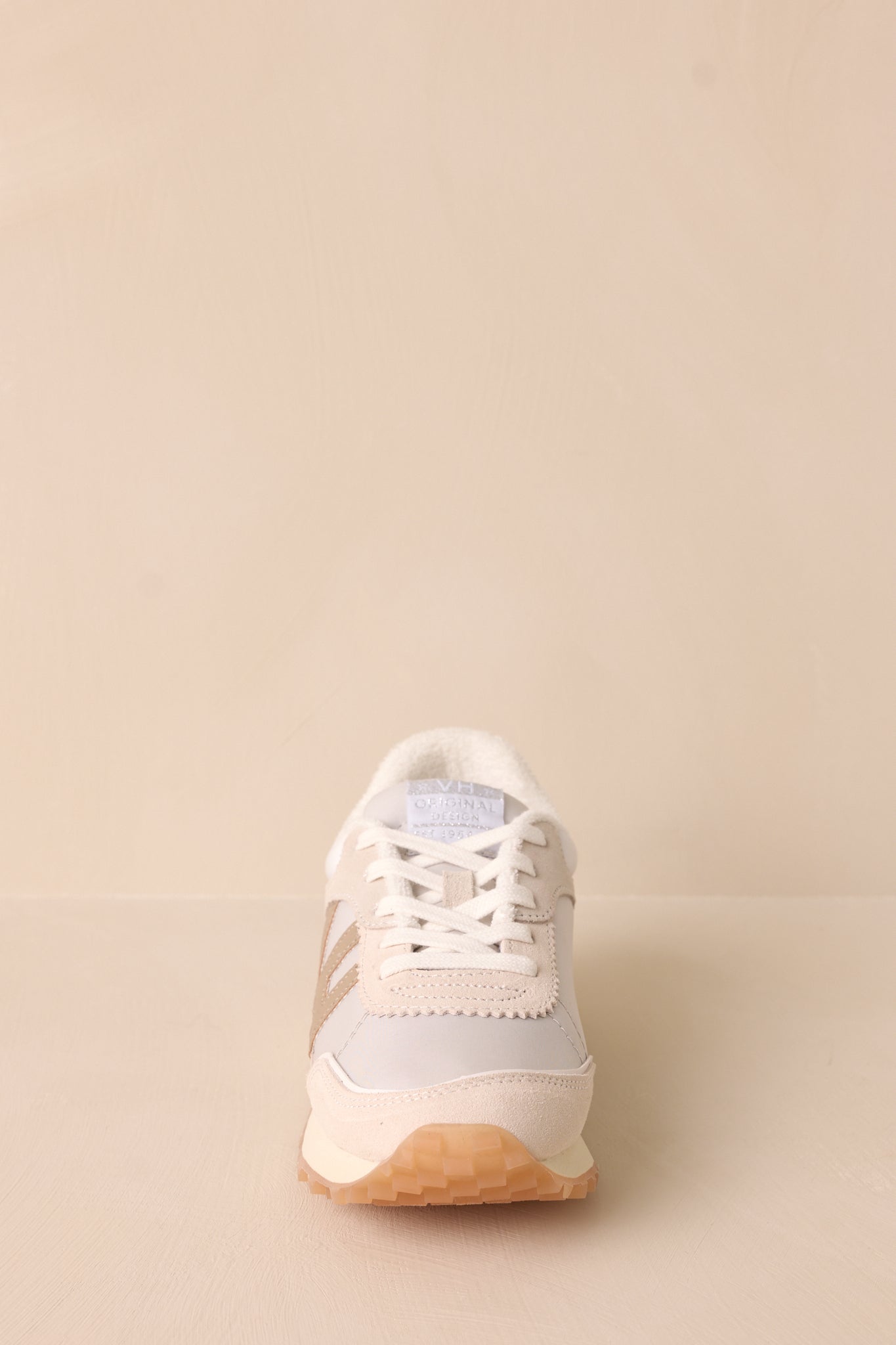 Front view of these white sneakers that features a rounded toe, functional laces, a slight platform and a heavily textured sole.