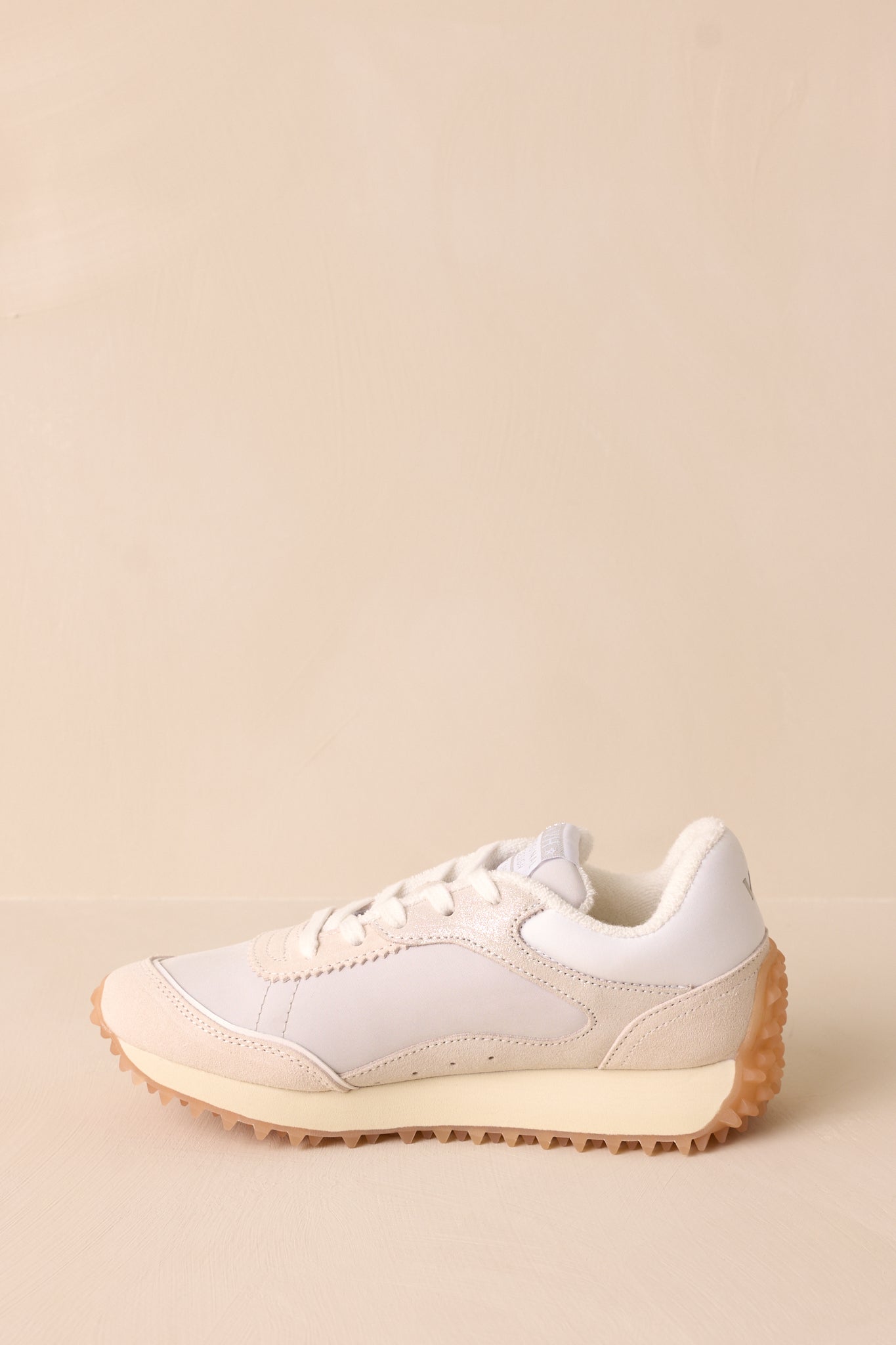 Side view of these white sneakers that features a rounded toe, functional laces, a slight platform and a heavily textured sole.