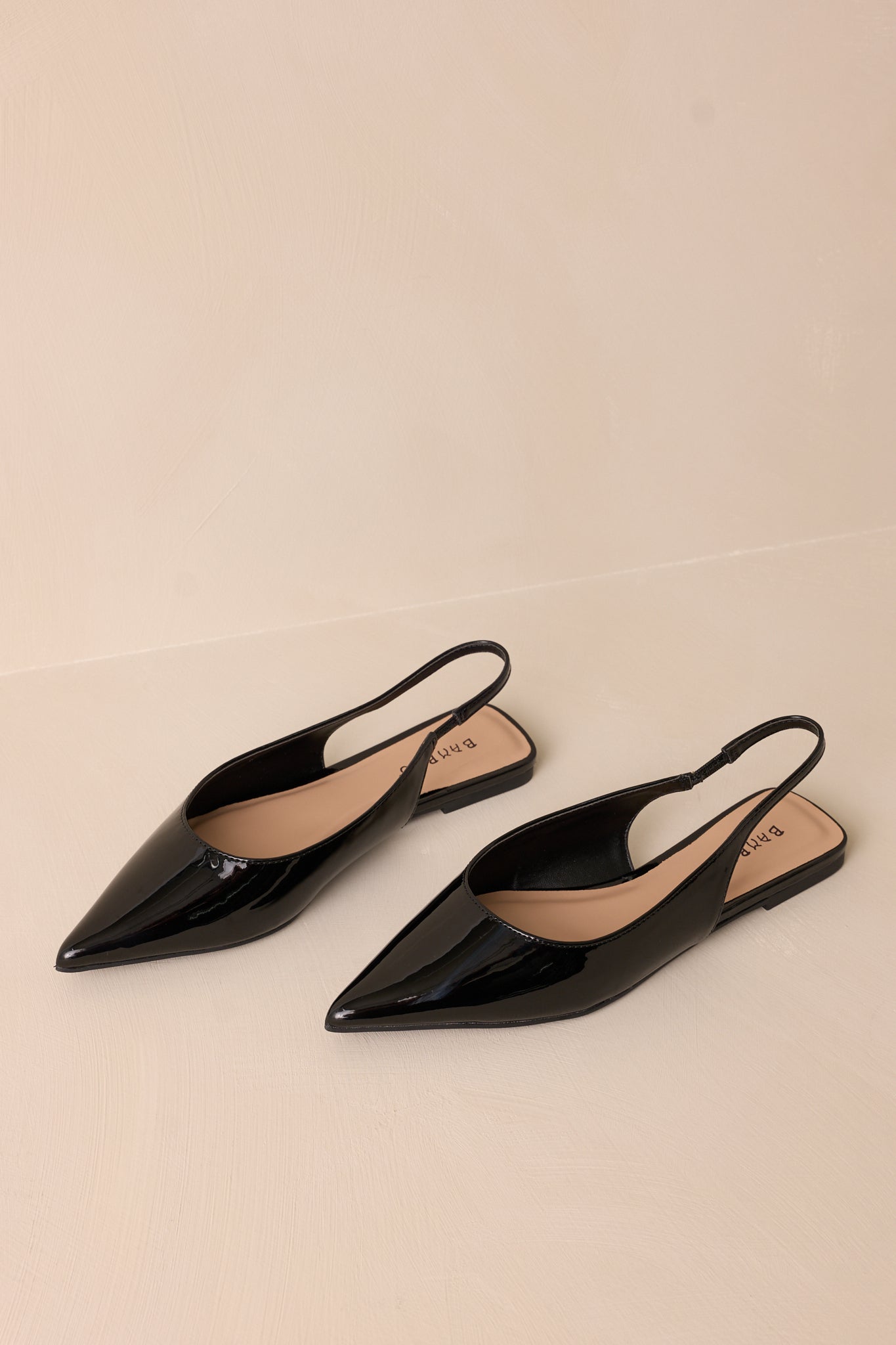 Focused view of the flats’ pointed toe, highlighting the glossy black patent finish and clean lines.