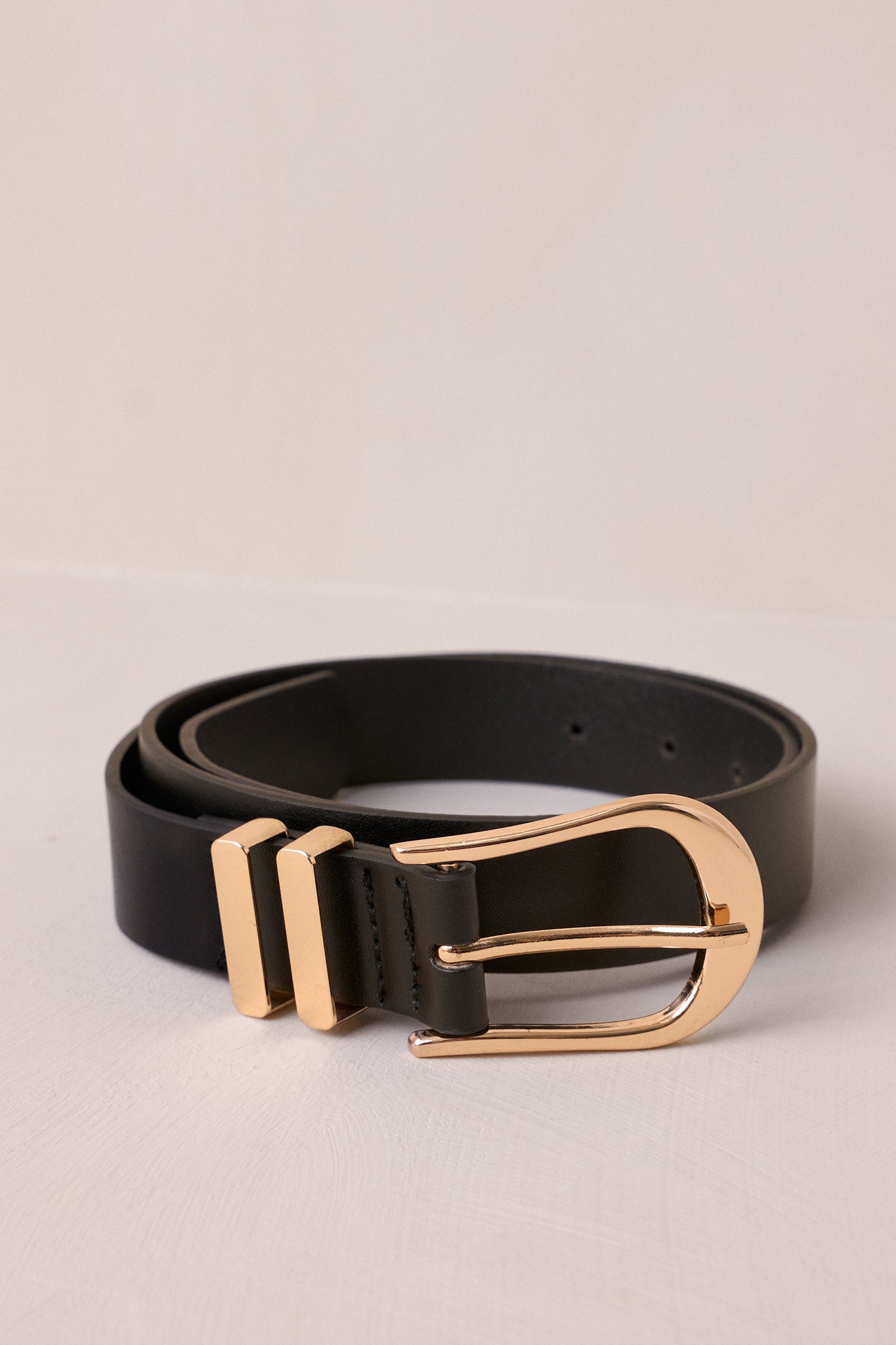 This black belt features a functional horseshoe pin buckle, gold hardware, and multiple belt holes for a custom fit.