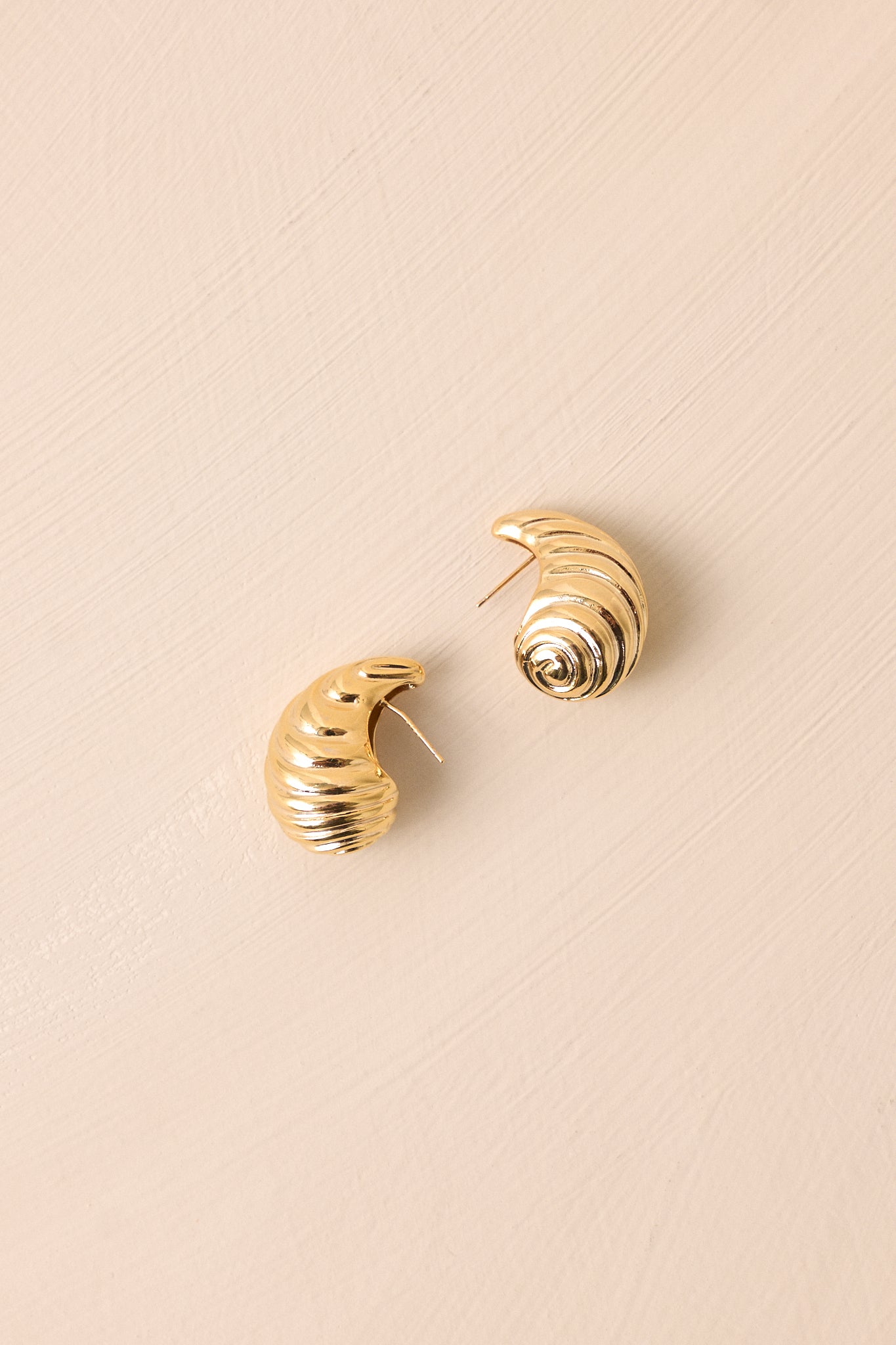 Detailed view of the earrings focusing on the intricate teardrop spiral pattern, showcasing the craftsmanship of the gold finish and the sturdy post backing for secure wear.