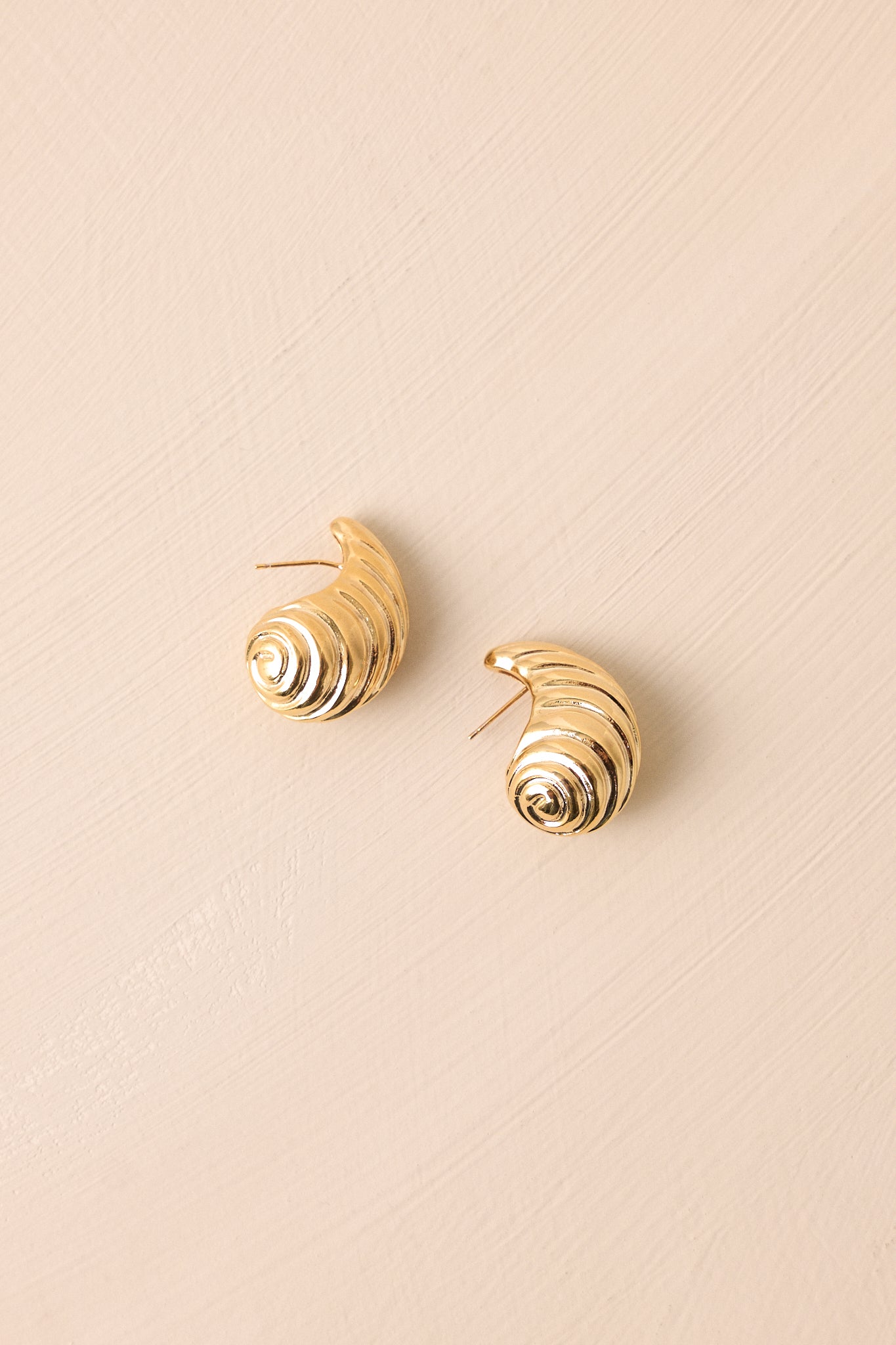 Angled shot of the earrings emphasizing the gold hardware and the unique spiral shape, with light reflecting off the textured surface, enhancing the luxurious appearance.