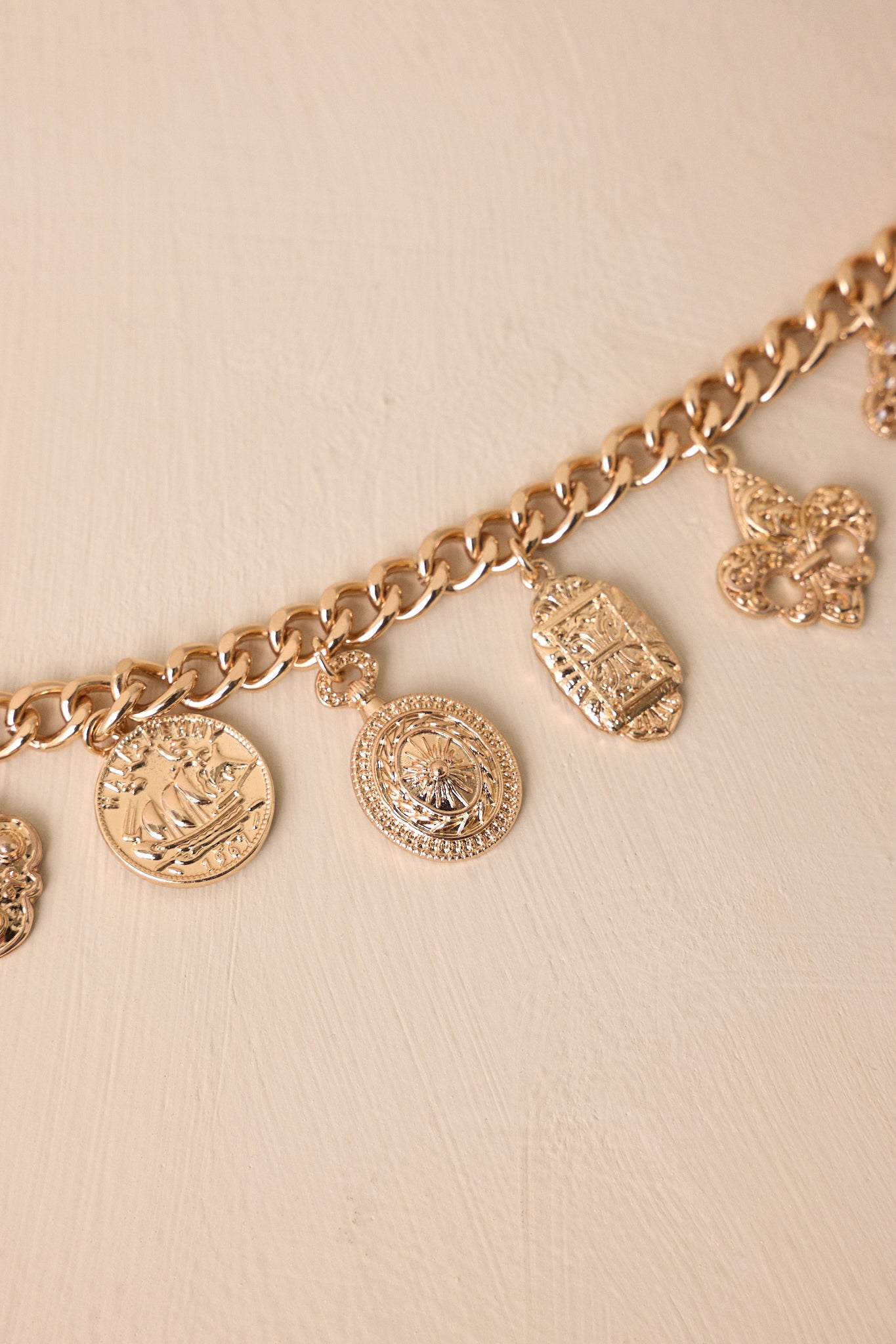 A zoomed-in view of the bracelet with four different gold pendants, emphasizing the variety in shapes and designs.