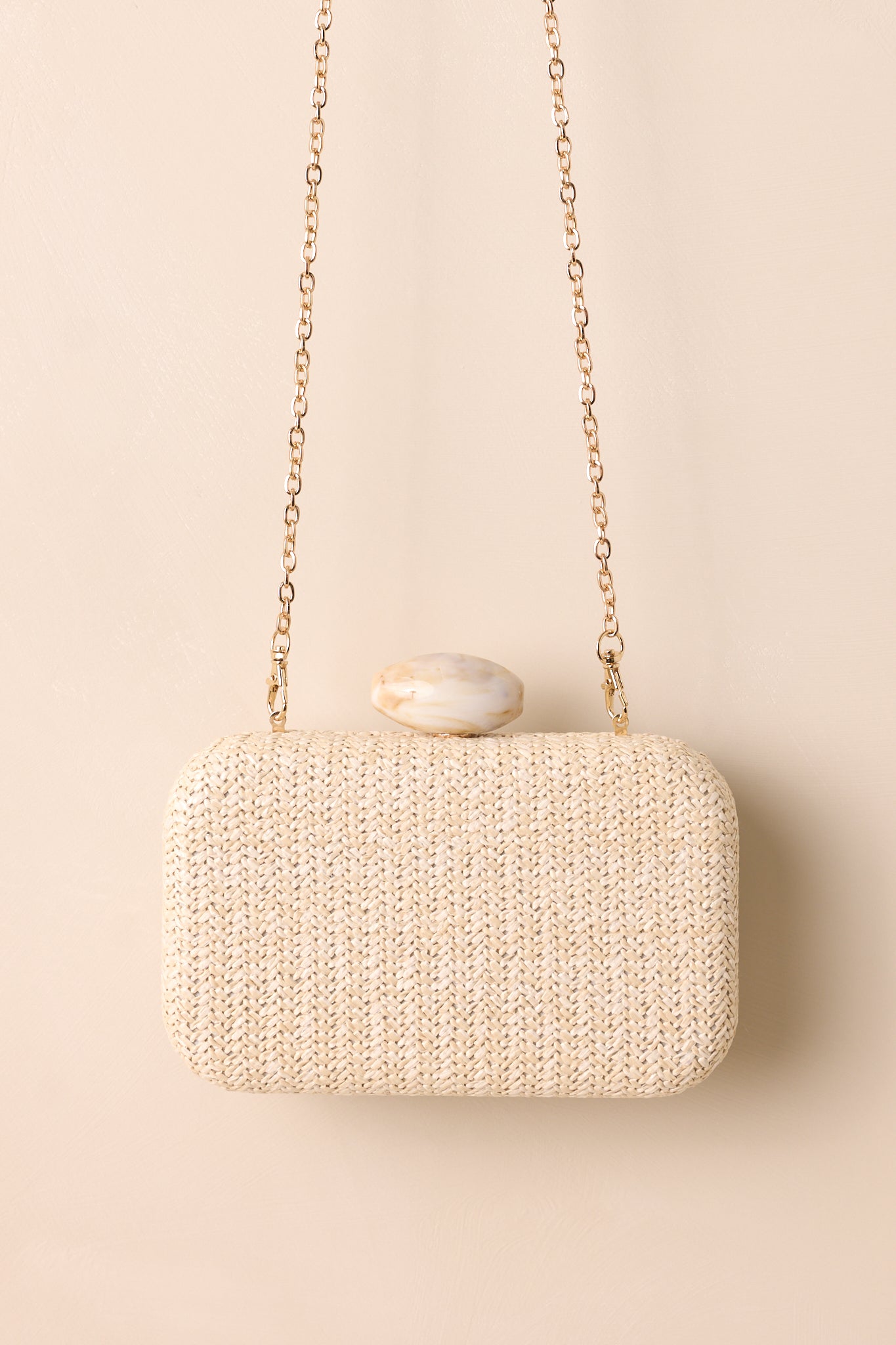 A full view of a chic clutch resting against a neutral beige background, displaying its clean lines and minimalist design.