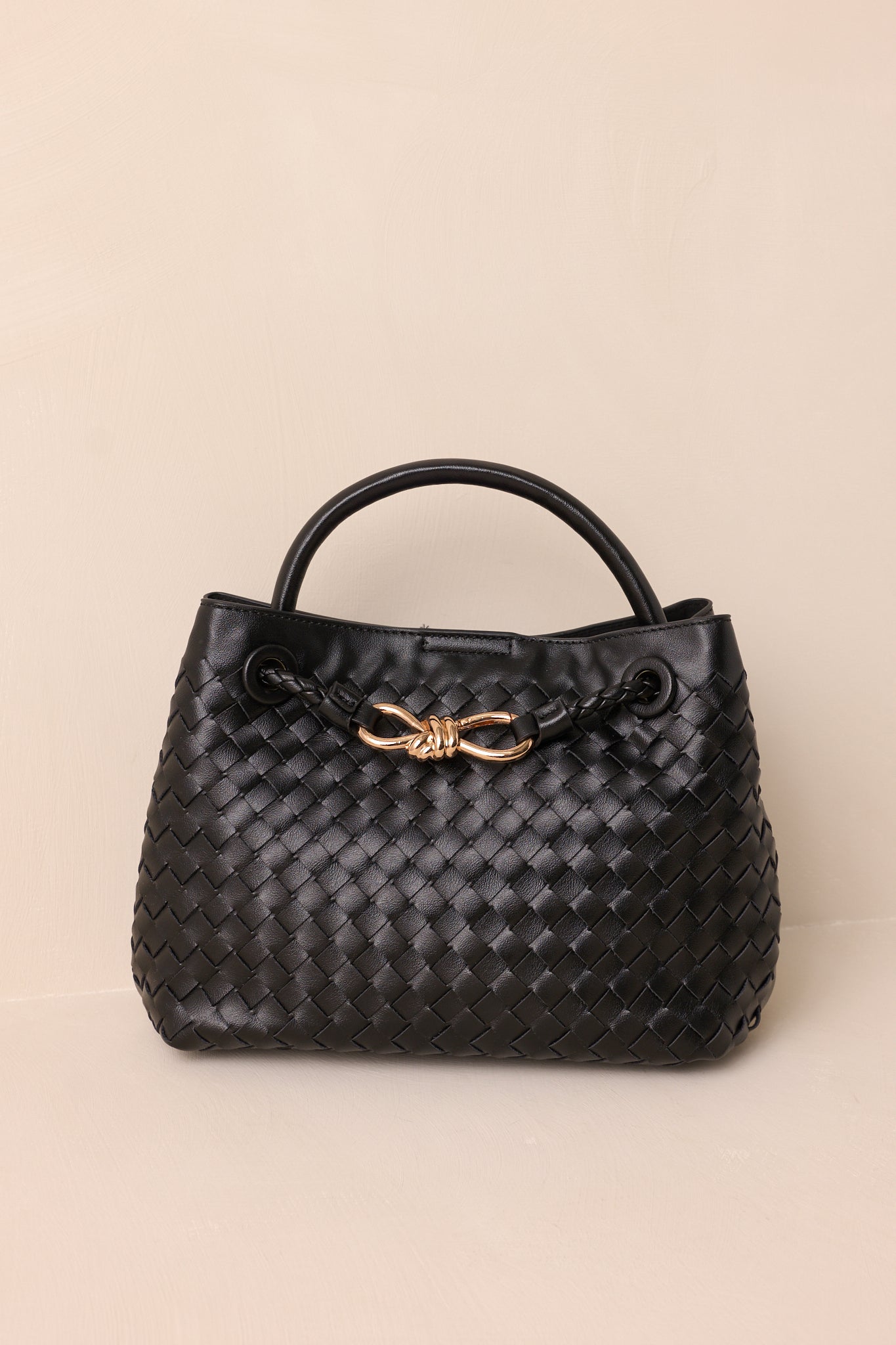 Front view of the black faux leather bag, showing the short handle for hand-held use and the sleek, structured silhouette.