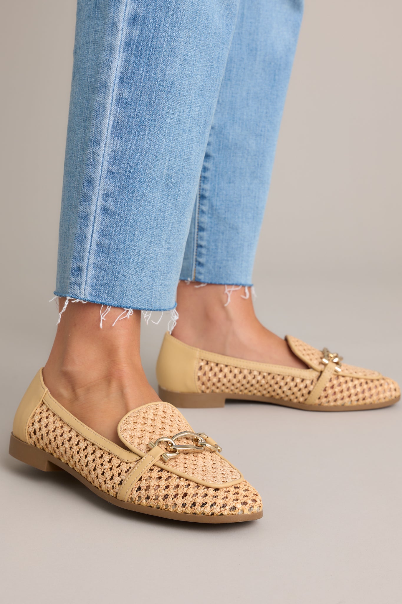 Close-up of these woven loafers that feature a rounded toe, gold accented strap, a breathable woven material and tan color blocking.