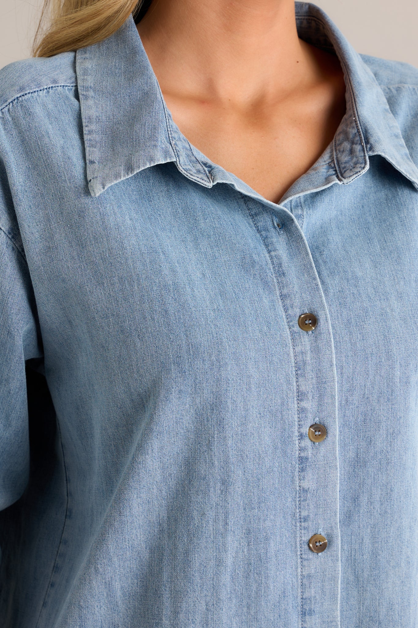 Close-up of the chambray top showing the collared neckline, functional buttons, and the fabric texture.