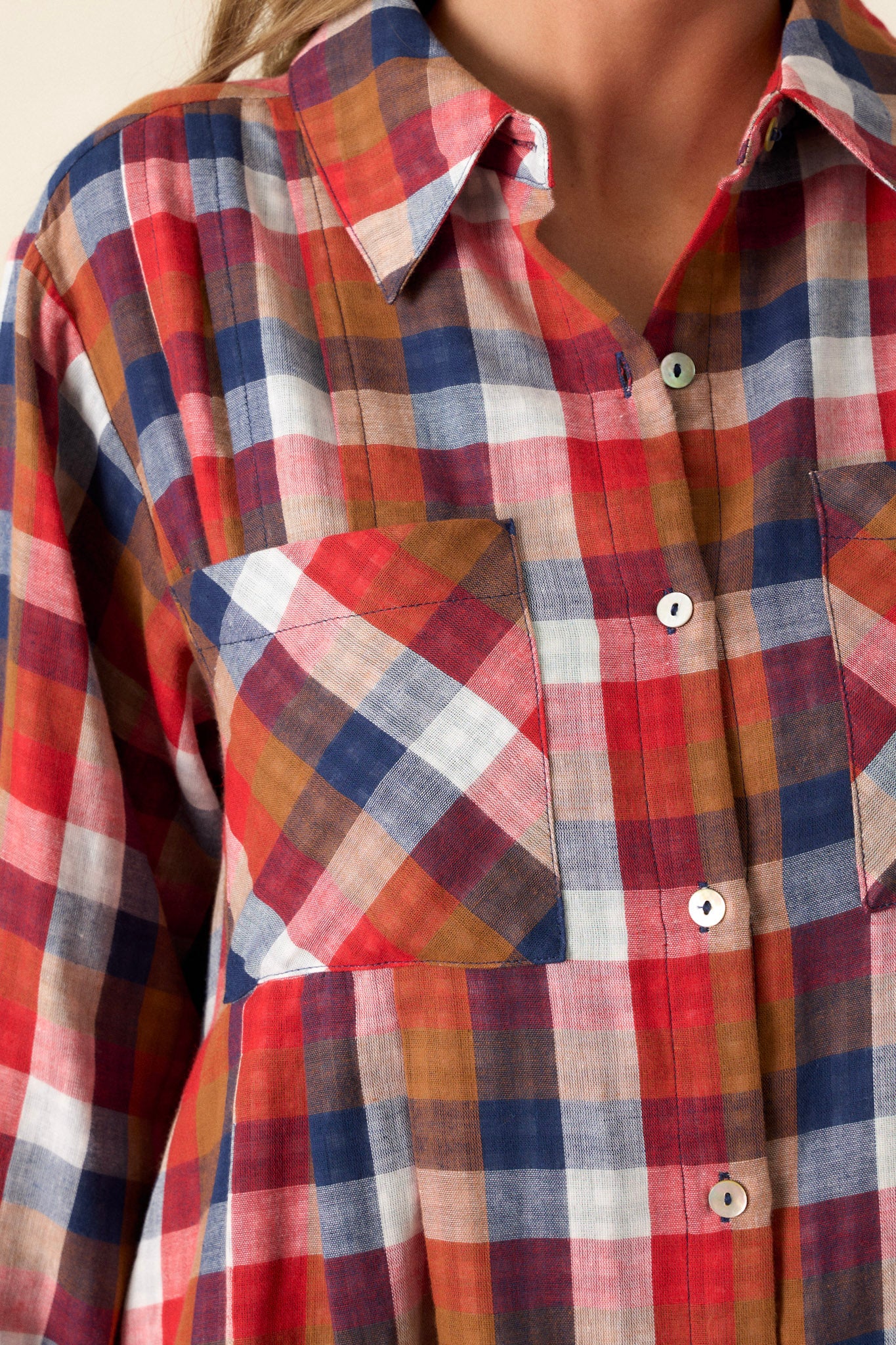 Close-up of the dress focusing on the collared neckline, the detail of the functional buttons, and the design of the four functional pockets.