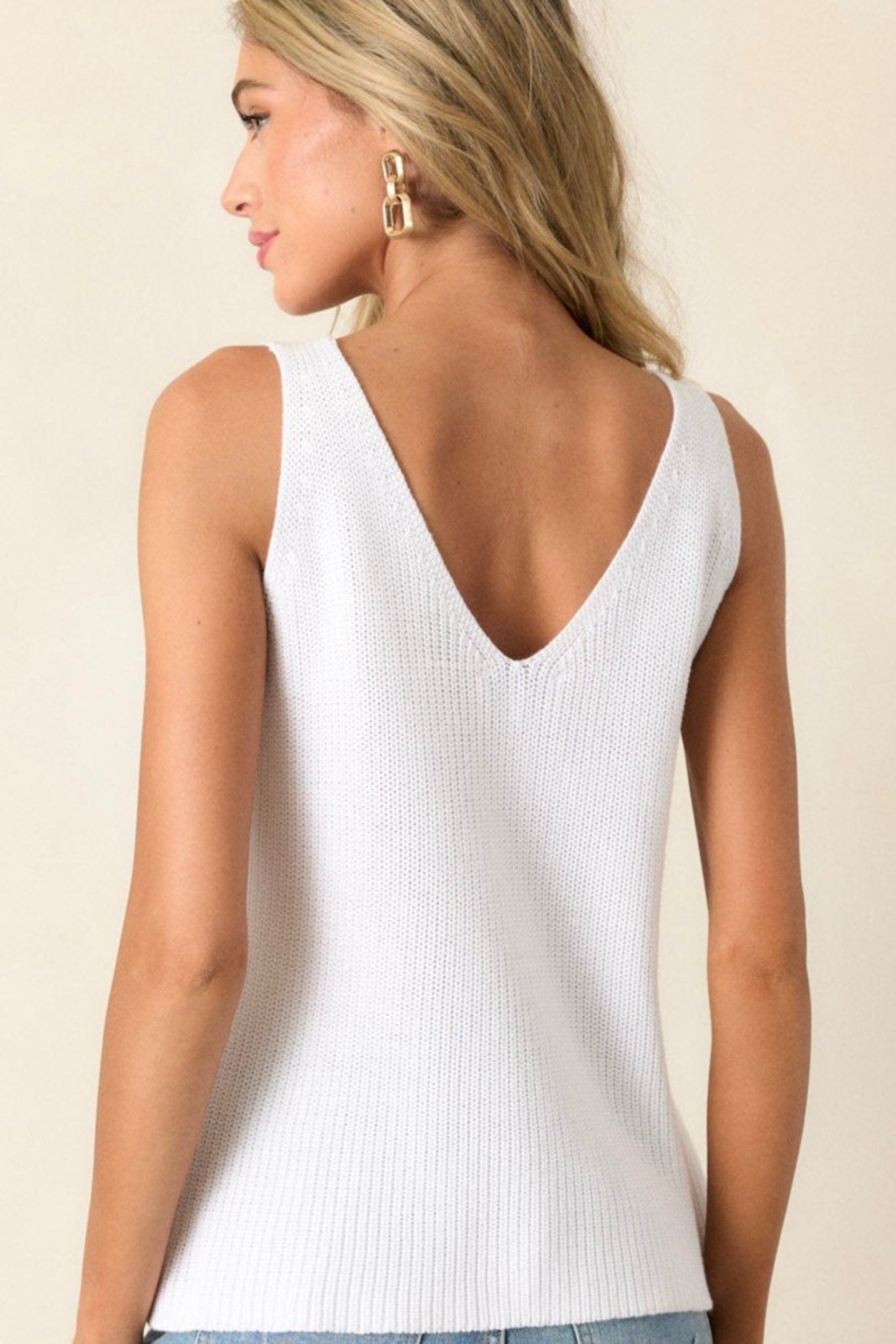 Back view of the ivory knit tank top highlighting the free cut hem, soft knit material, and the sleeveless design