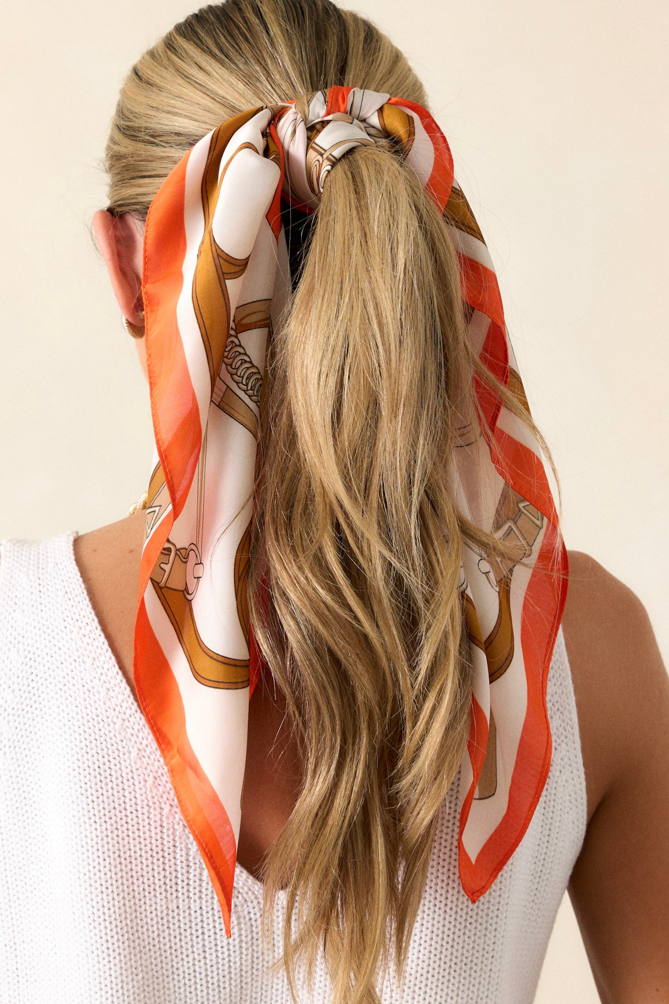 Back view of this orange scarf that features a satin material, and a multicolored print.