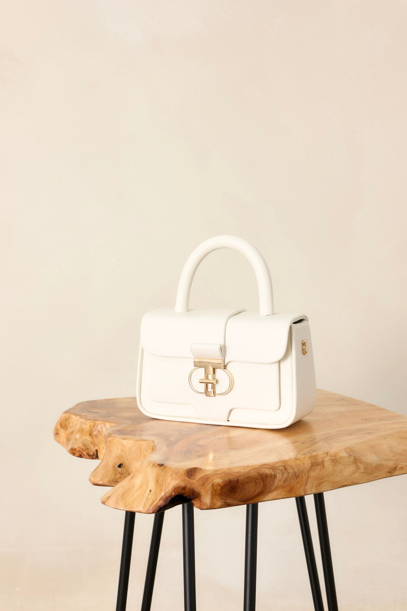 This white handbag features a gold hardware, an inside pocket, an included matching wallet, optional crossbody strap, and a top handle design.