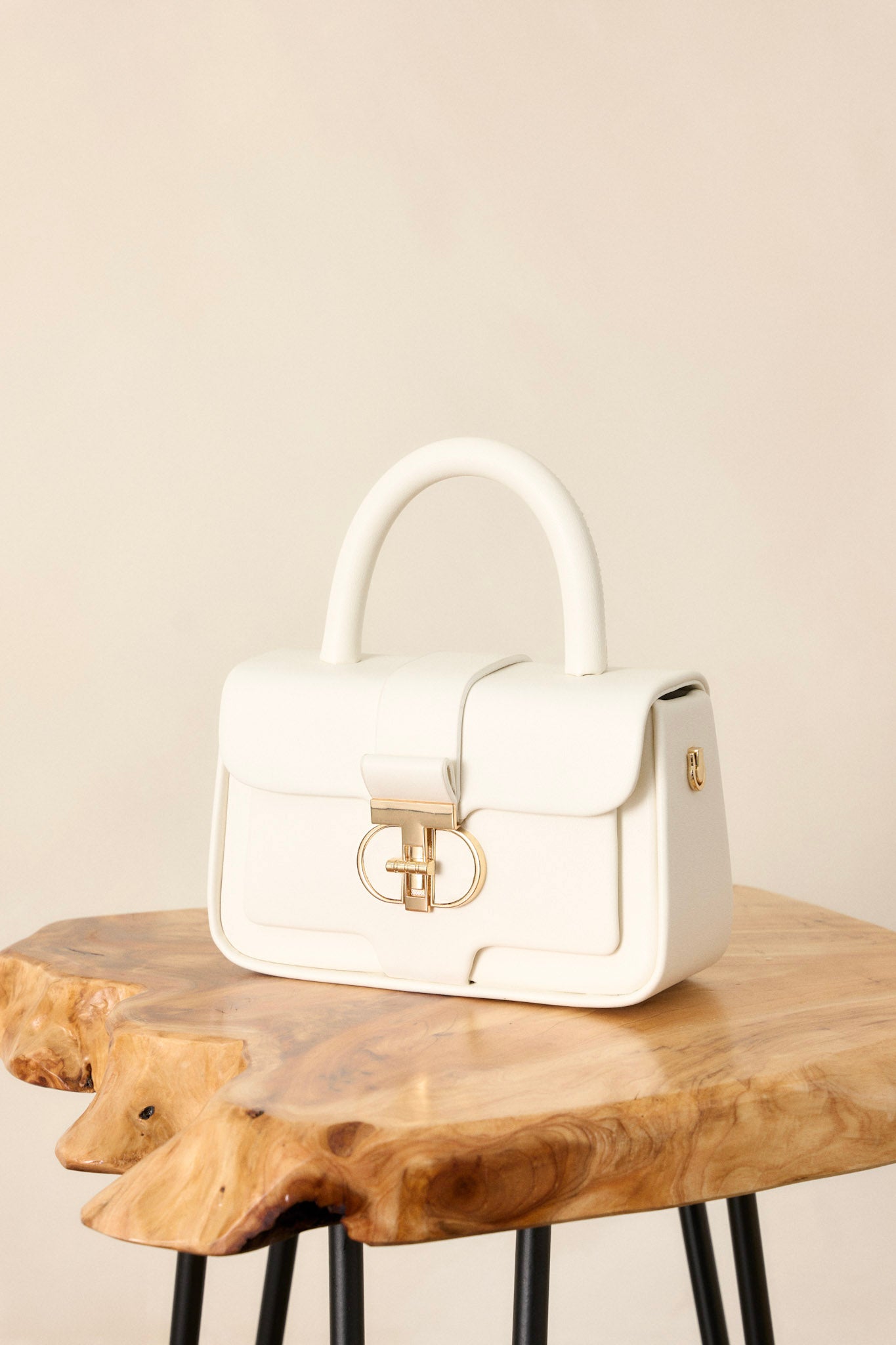 Close up view of this white handbag featuring gold hardware, an inside pocket, an included matching wallet, optional crossbody strap, and a top handle design.&nbsp;&nbsp;