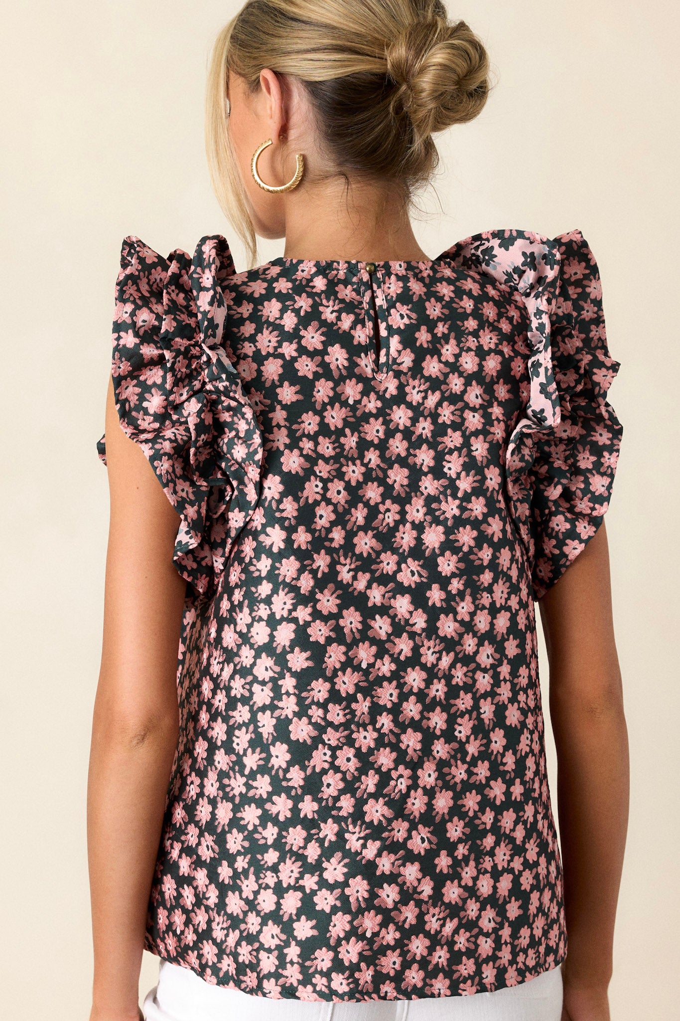 Back view of a hunter green floral top highlighting the high rounded neckline and the ruffled sleeveless design.