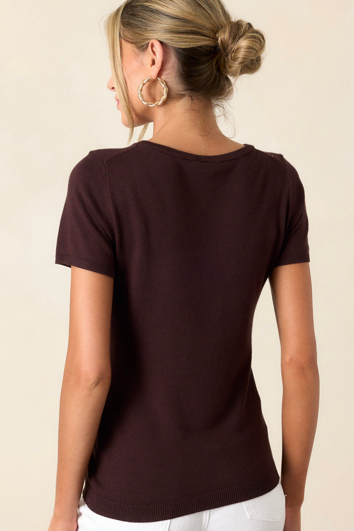 Back view of the dark brown sweater top highlighting the smooth back panel, ribbed hem, and short sleeves