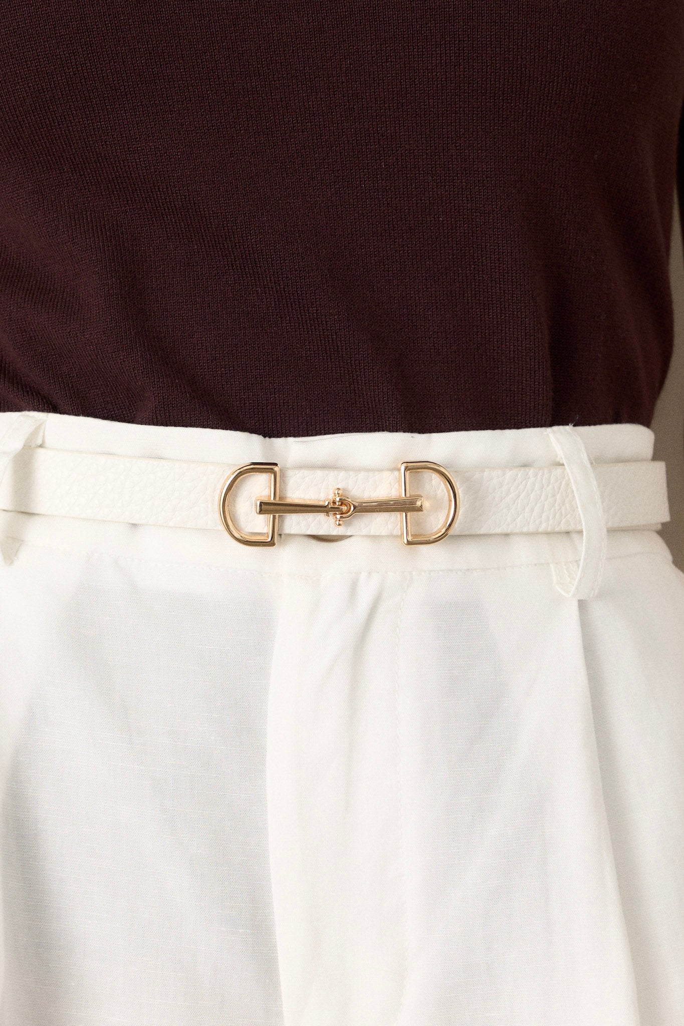 This white belt features gold hardware, an anchor closure, and a textured design.