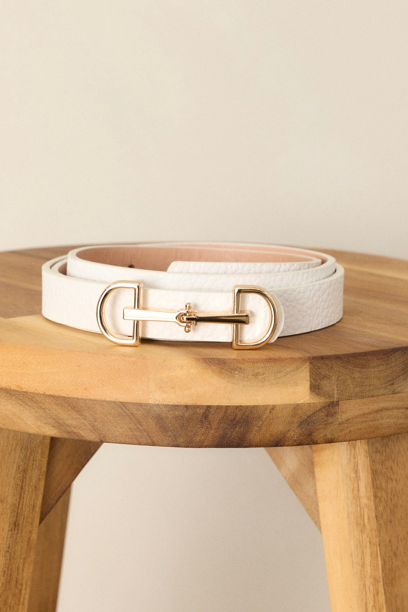 Close-up of this white belt that  features gold hardware, an anchor closure, and a textured design.